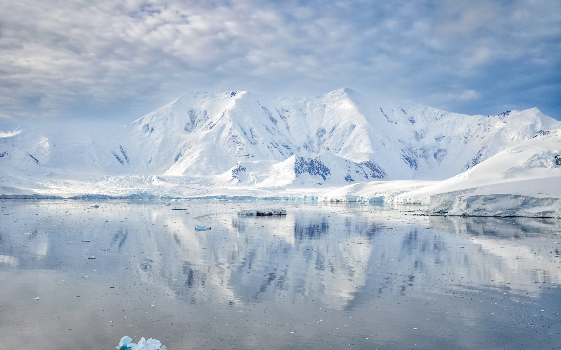 Заснеженные горы под белыми облаками у океана, Антарктида 