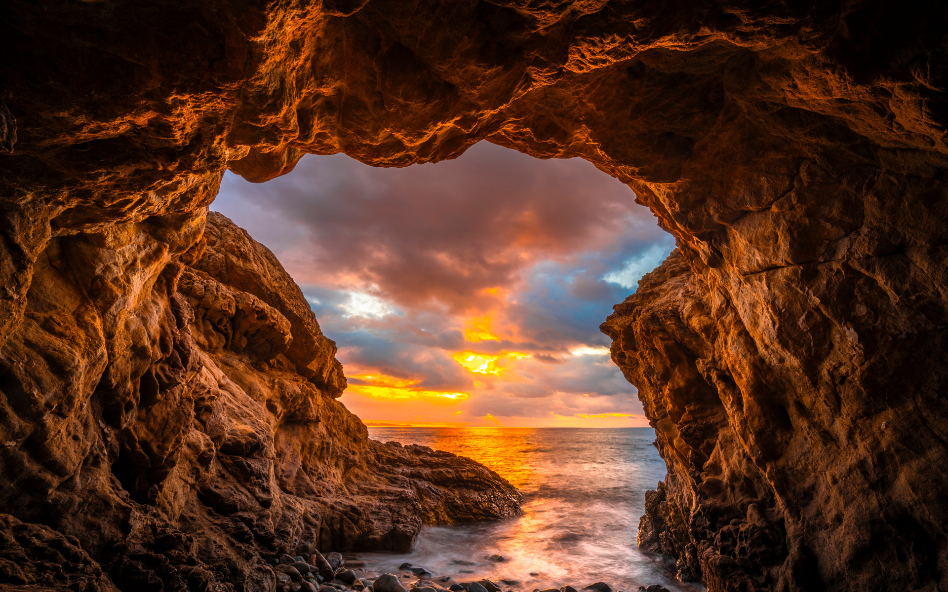 Арка в горе на закате солнца на пляже Малибу, США