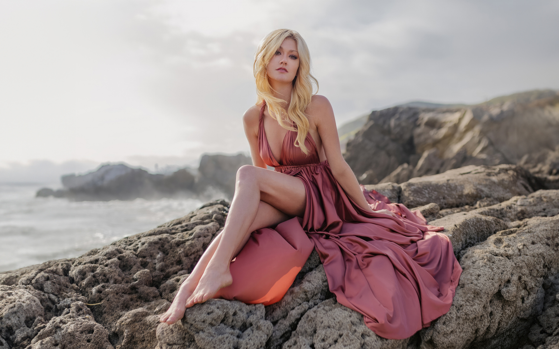 Актриса Кэтрин Макнамара сидит на камне у моря