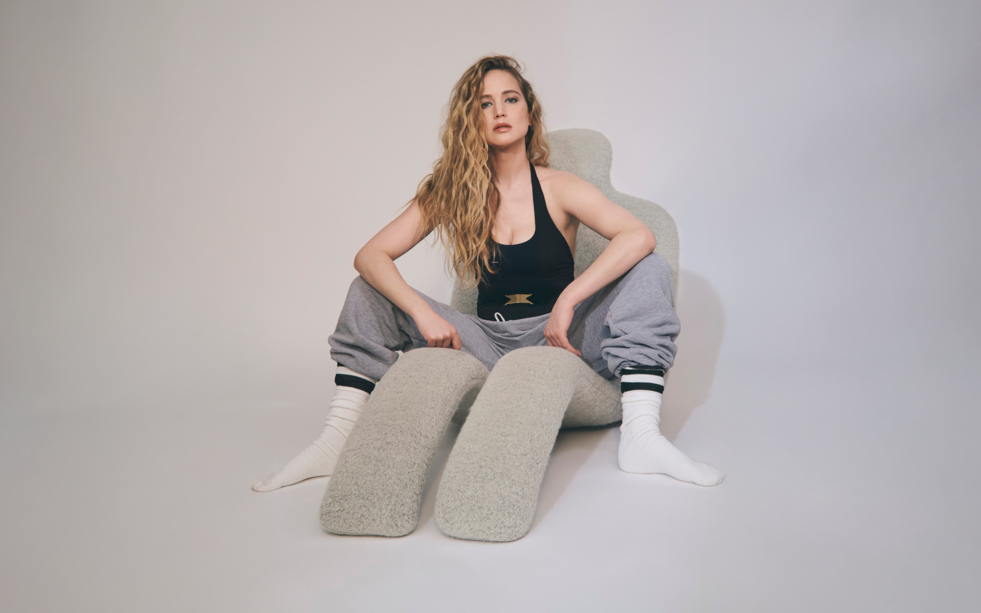 Красивая актриса Дженнифер Лоуренс  сидит на сером кресле