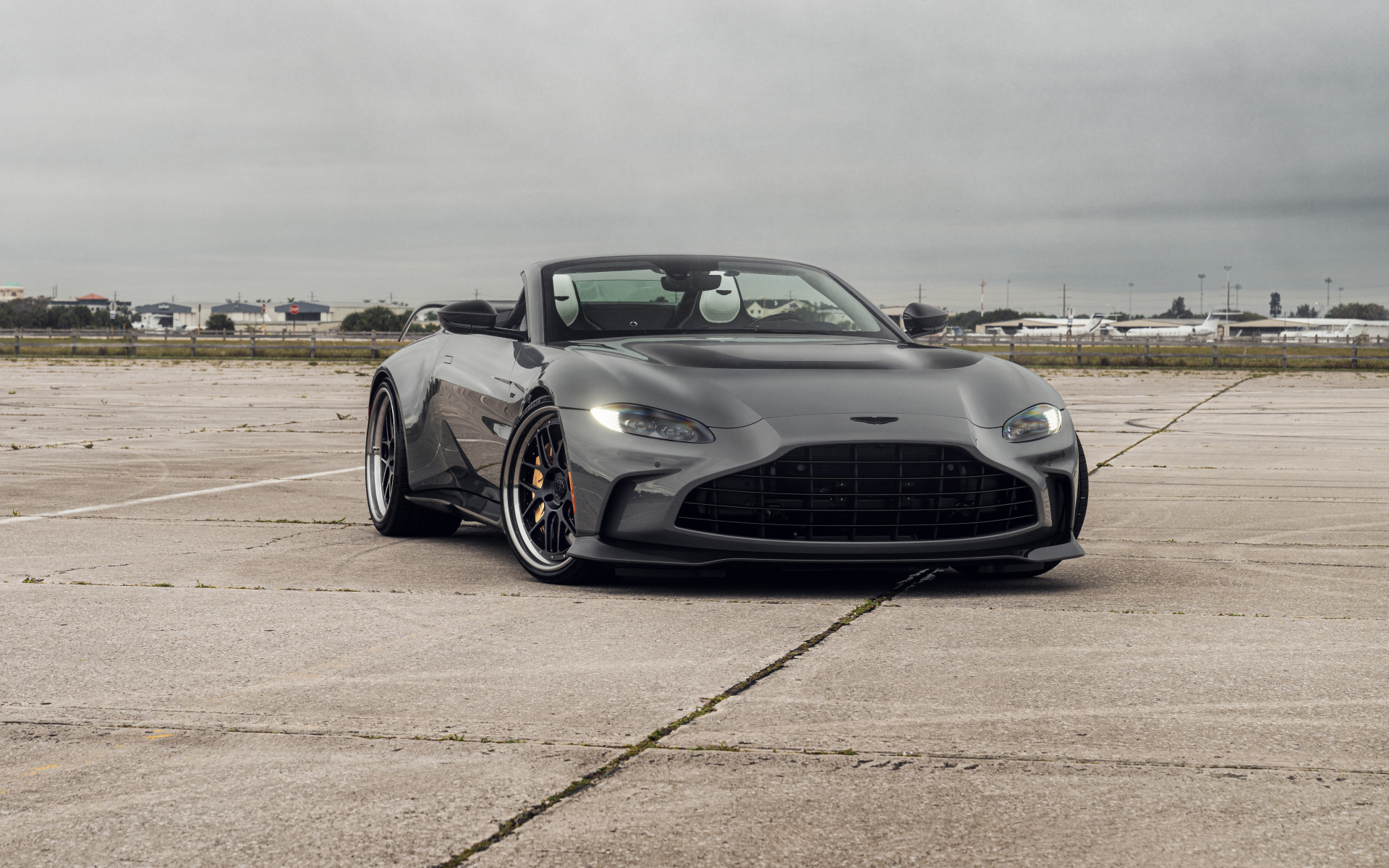 Серый автомобиль Aston Martin Vantage V12 Roadster на взлетной полосе