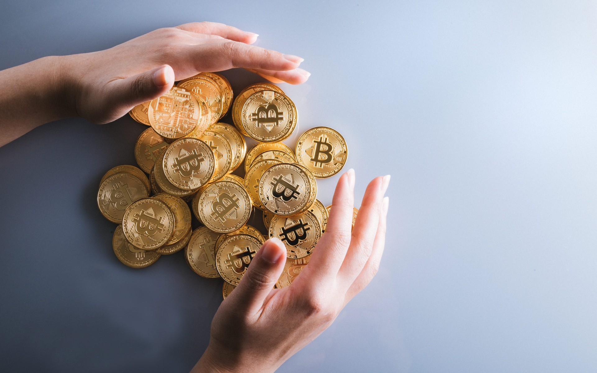 Много монет биткоин с руками на сером фоне