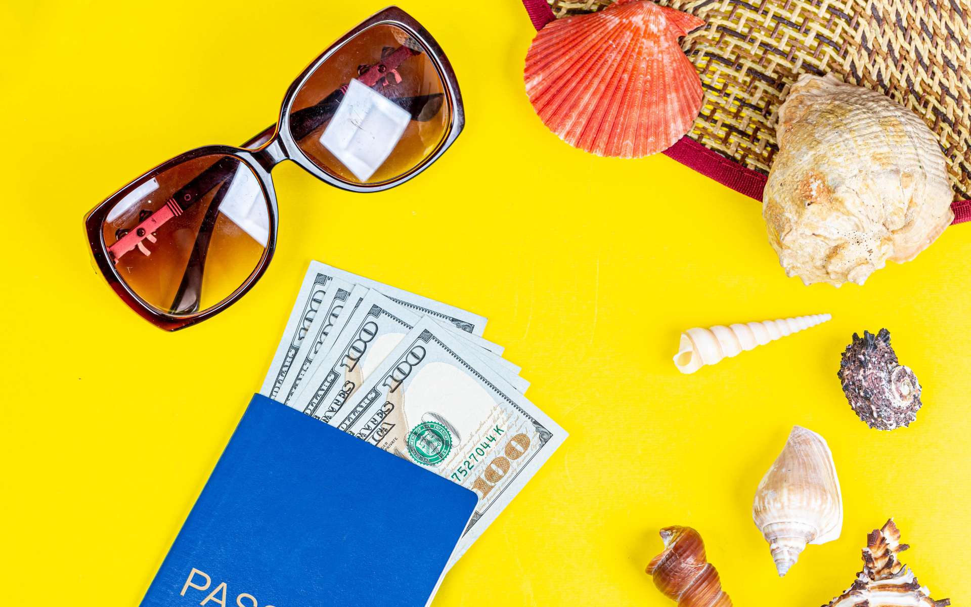 Очки, доллары с паспортом и ракушки на желтом фоне