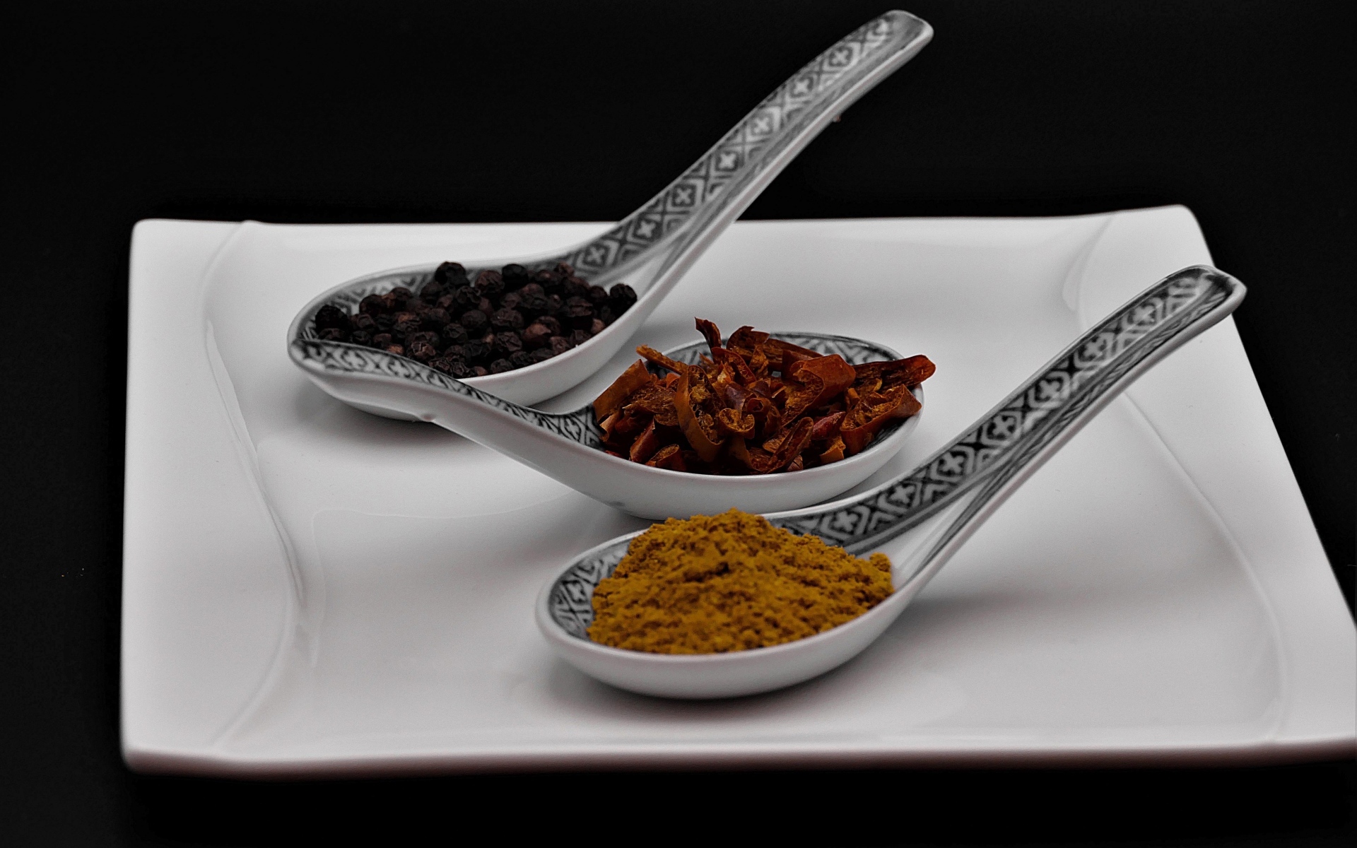 Ароматные специи в ложках на белой тарелке