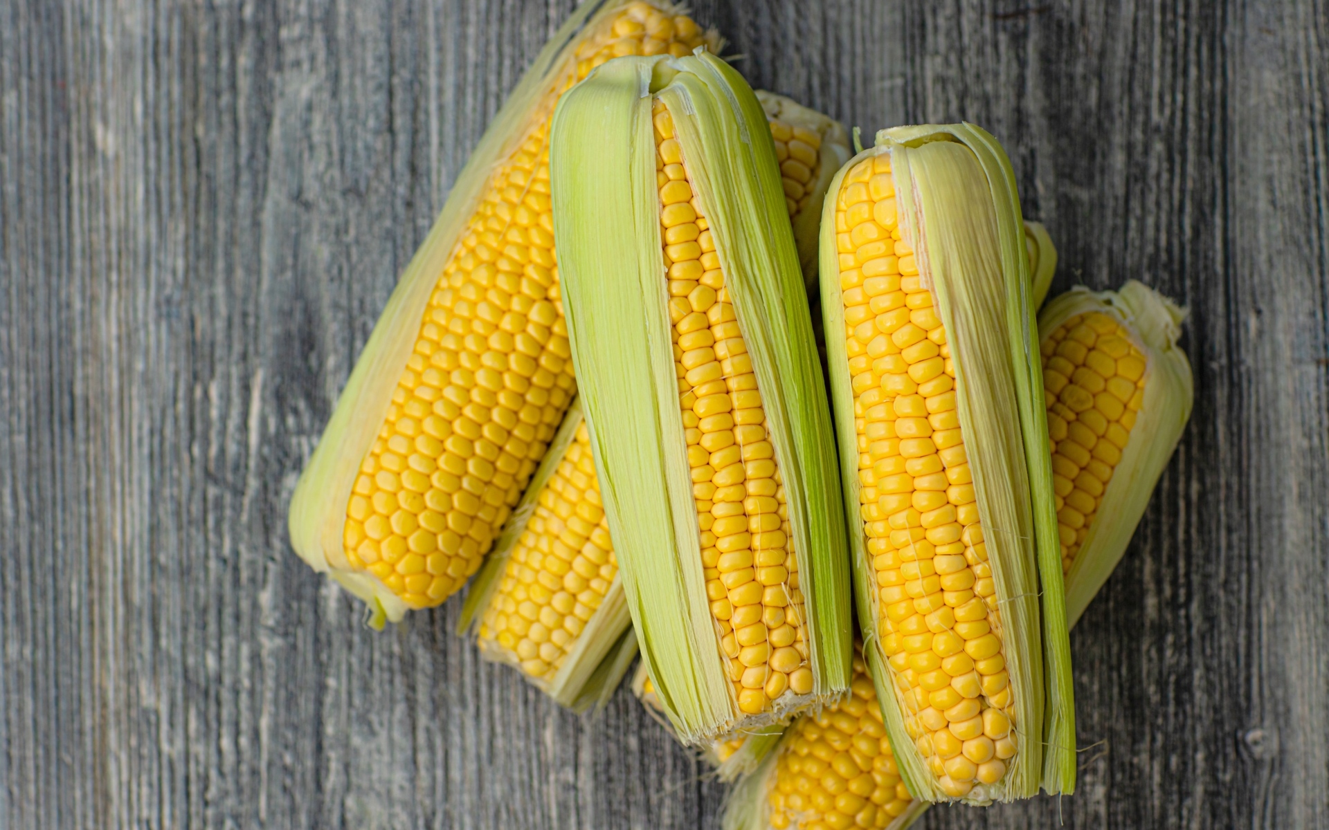 Початки кукурузы с листьями на сером столе