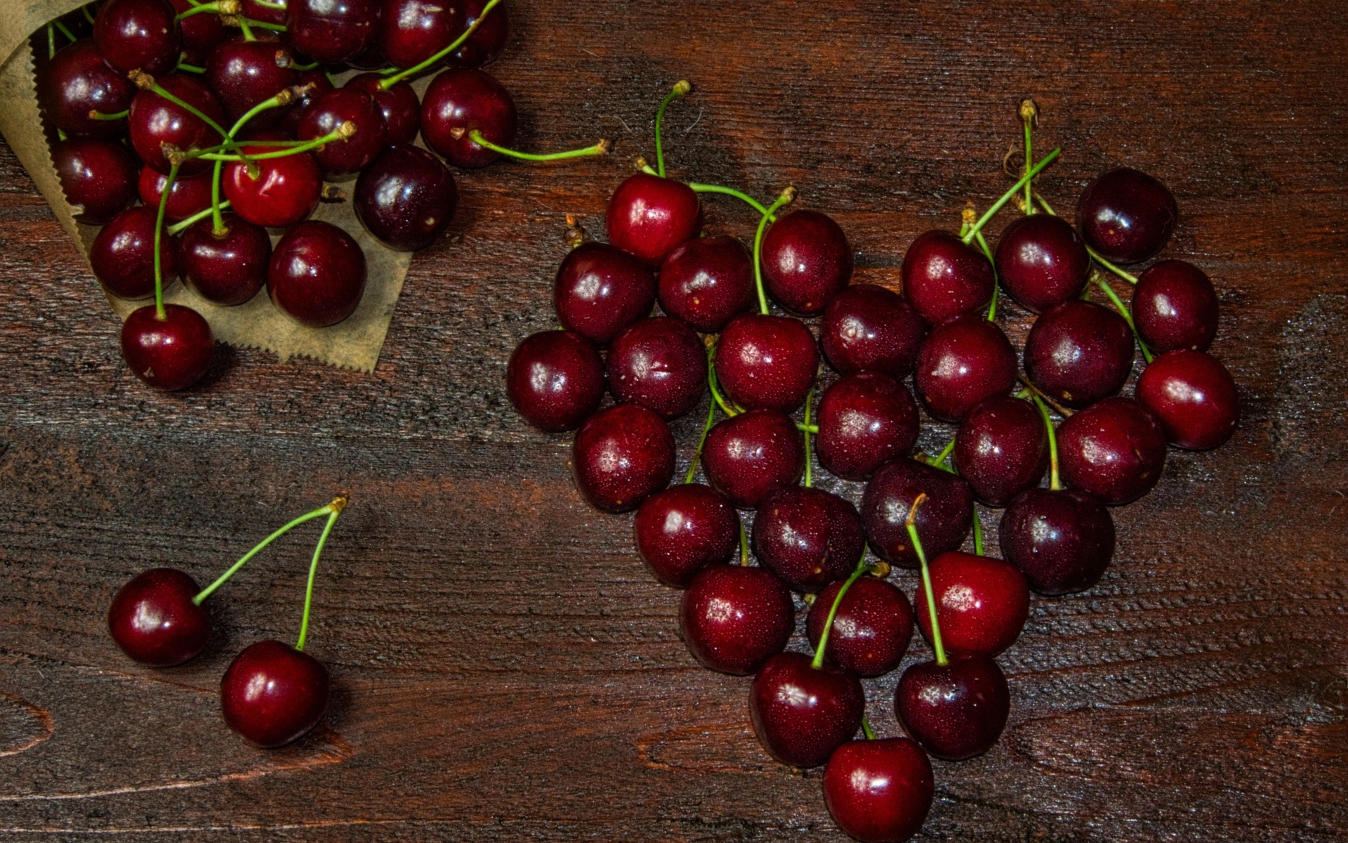 Сердце из спелых ягод черешни на деревянном столе