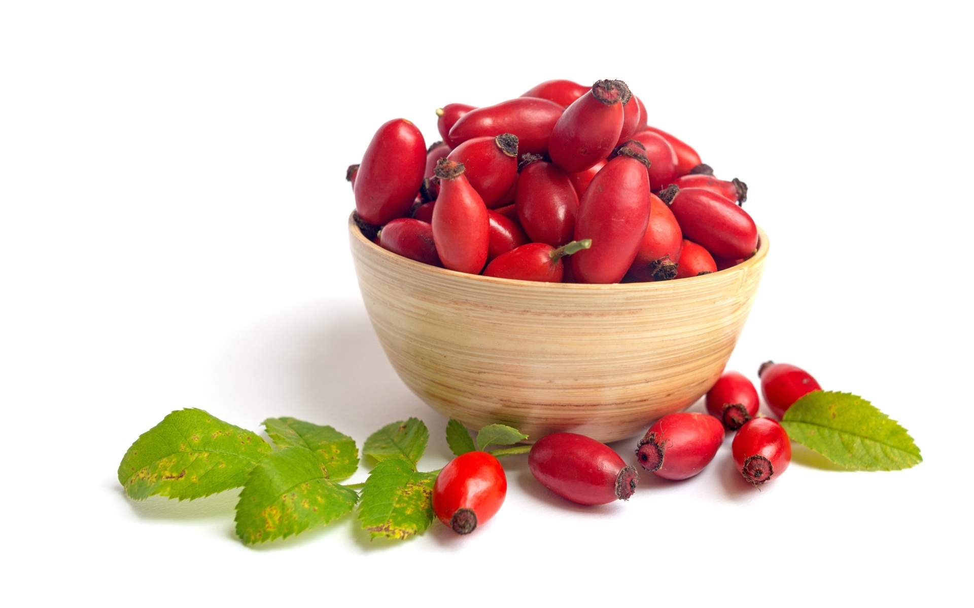 Тарелка с красными плодами шиповника на белом фоне