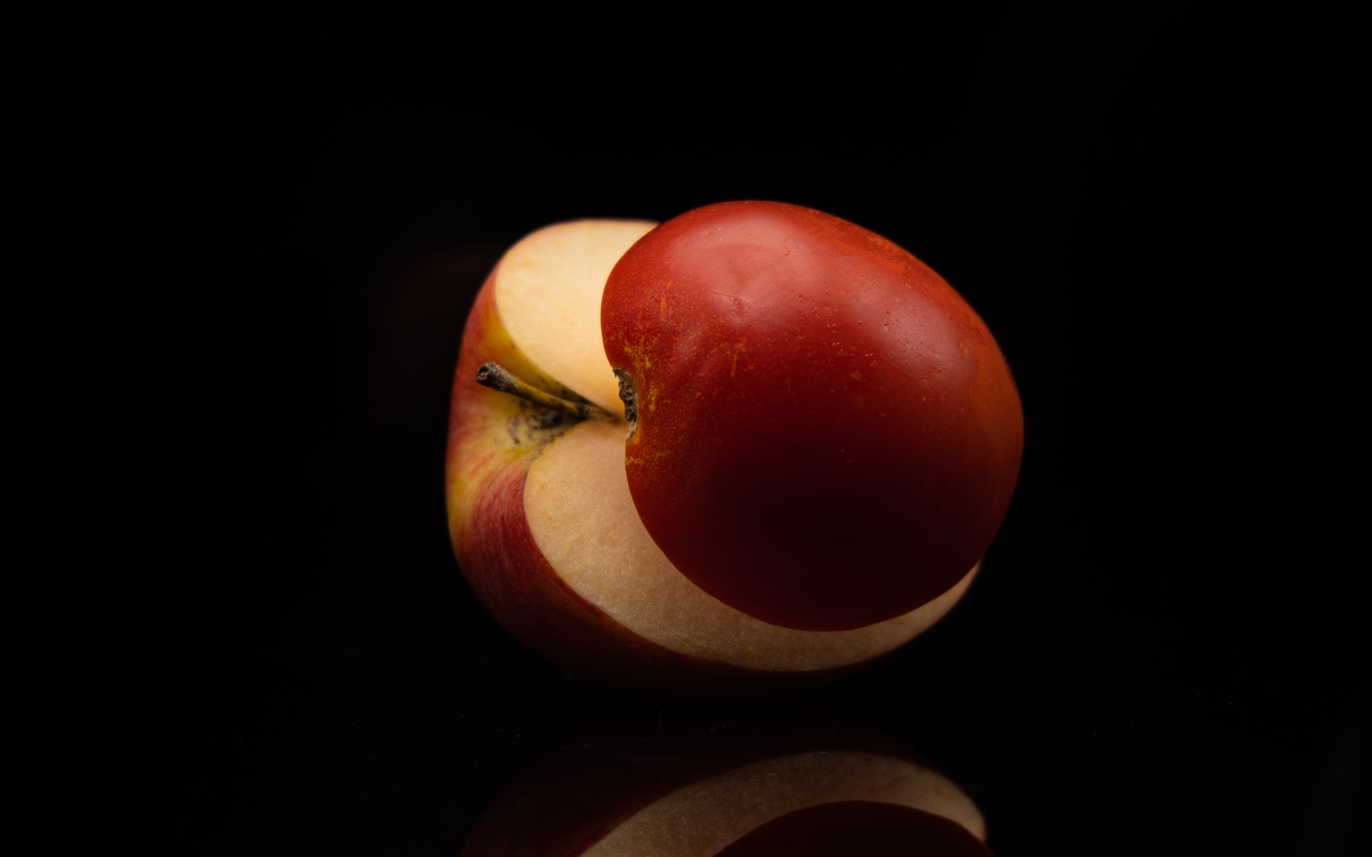 Разрезанное на половинки красное яблоко на черном фоне