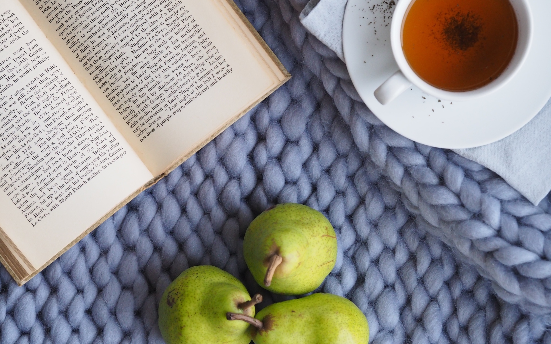 Три зеленые груши на столе с чаем и книгой