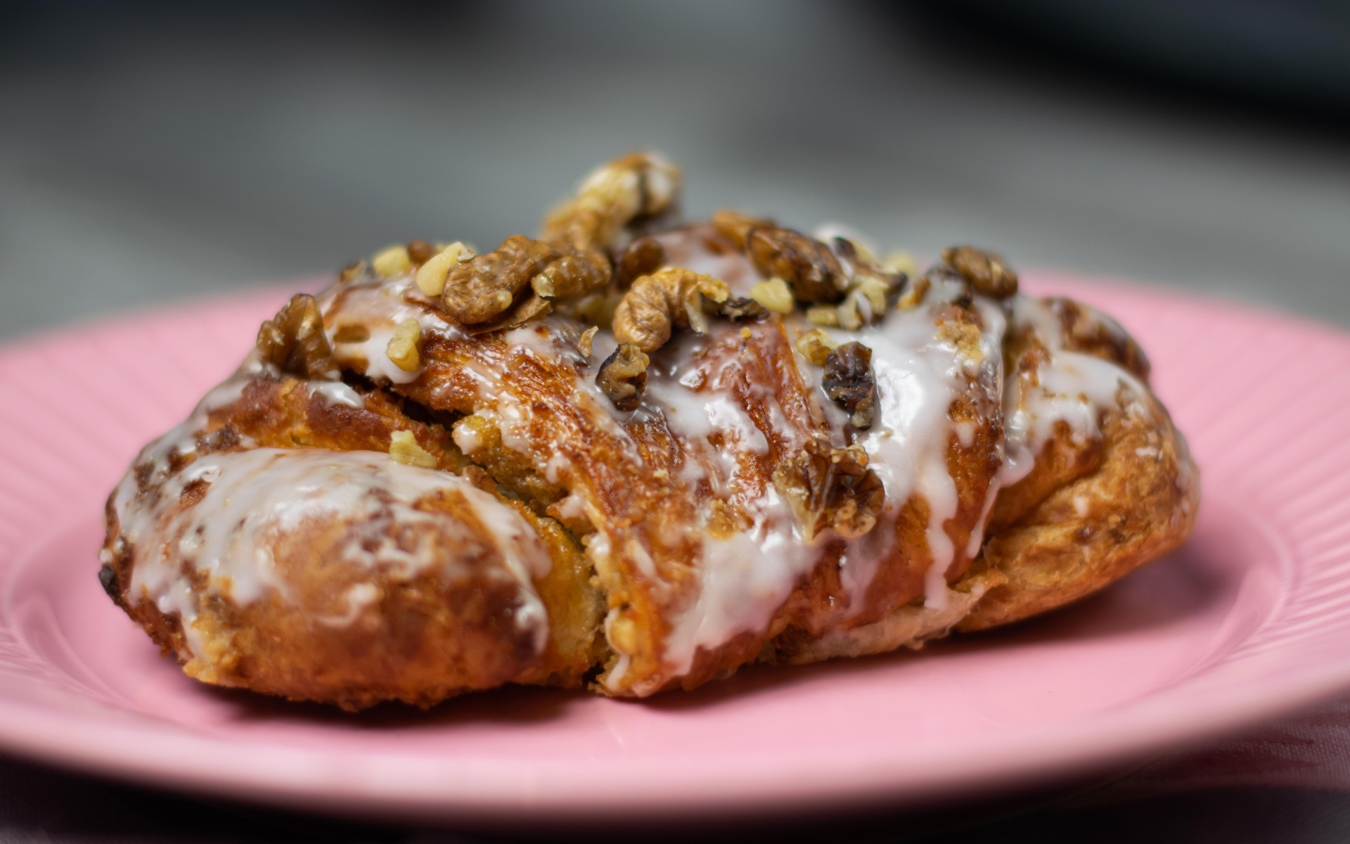Круассан с кремом и грецкими орехами на розовой тарелке