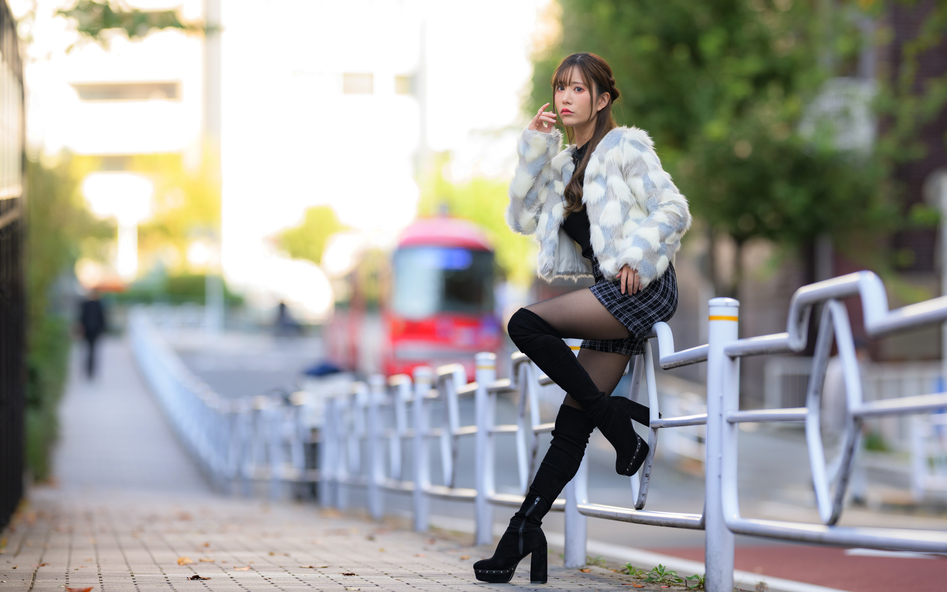 Азиатка в шубе стоит у забора