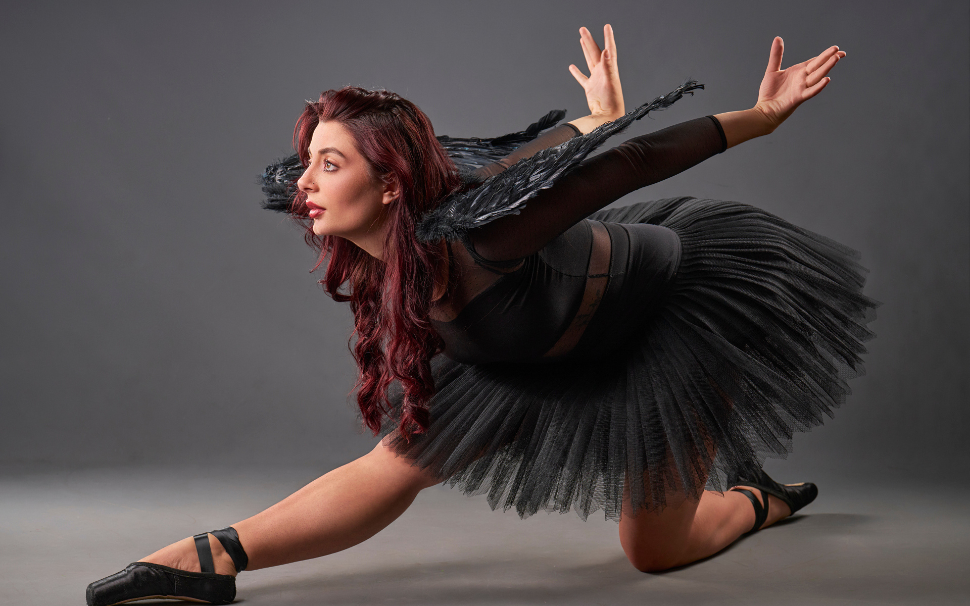 Девушка в черном костюме с крыльями танцует