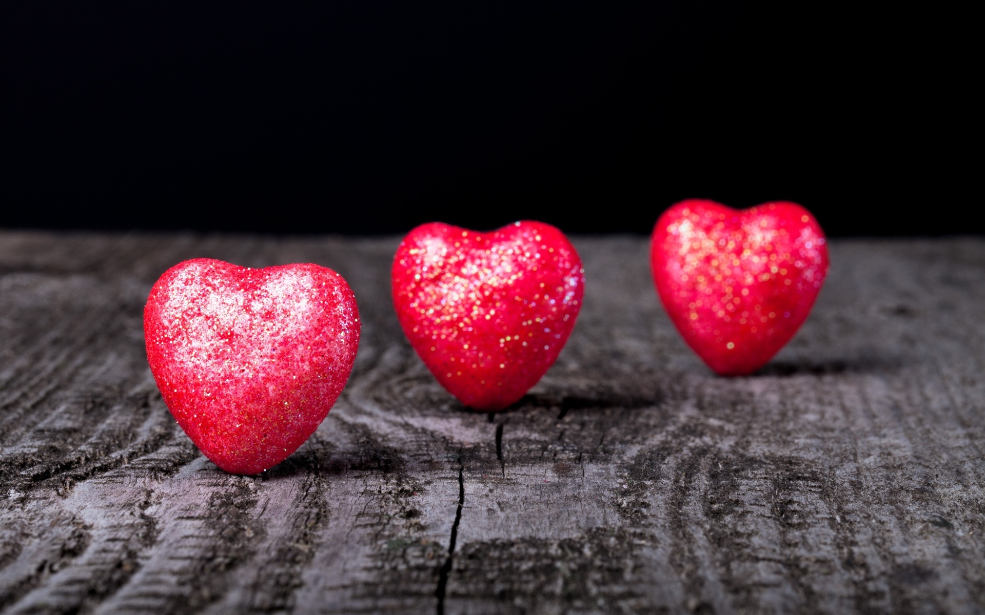 Три блестящих красных сердца на деревянном столе