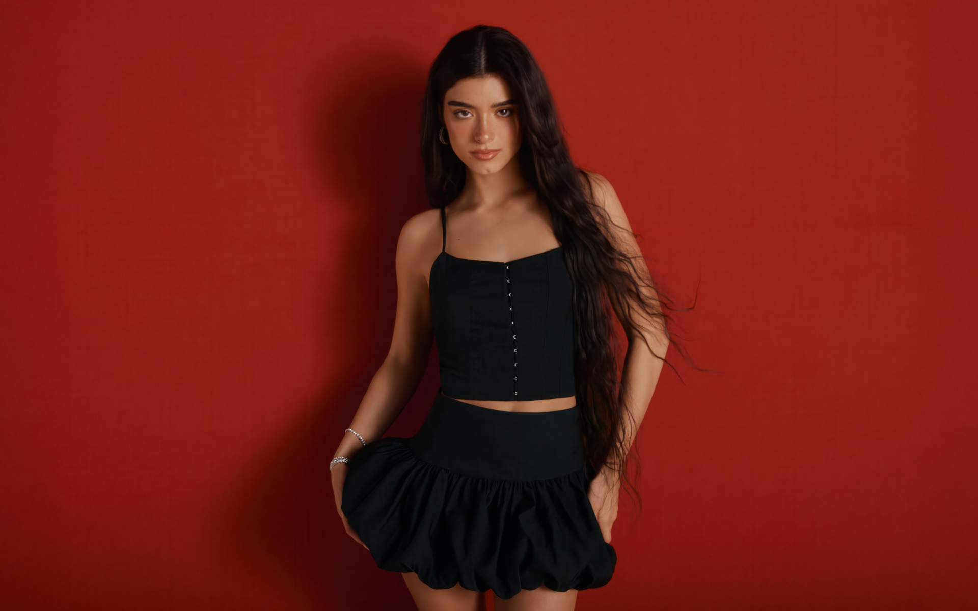 Популярная девушка Дикси Дамелио в черном костюме на красном фоне