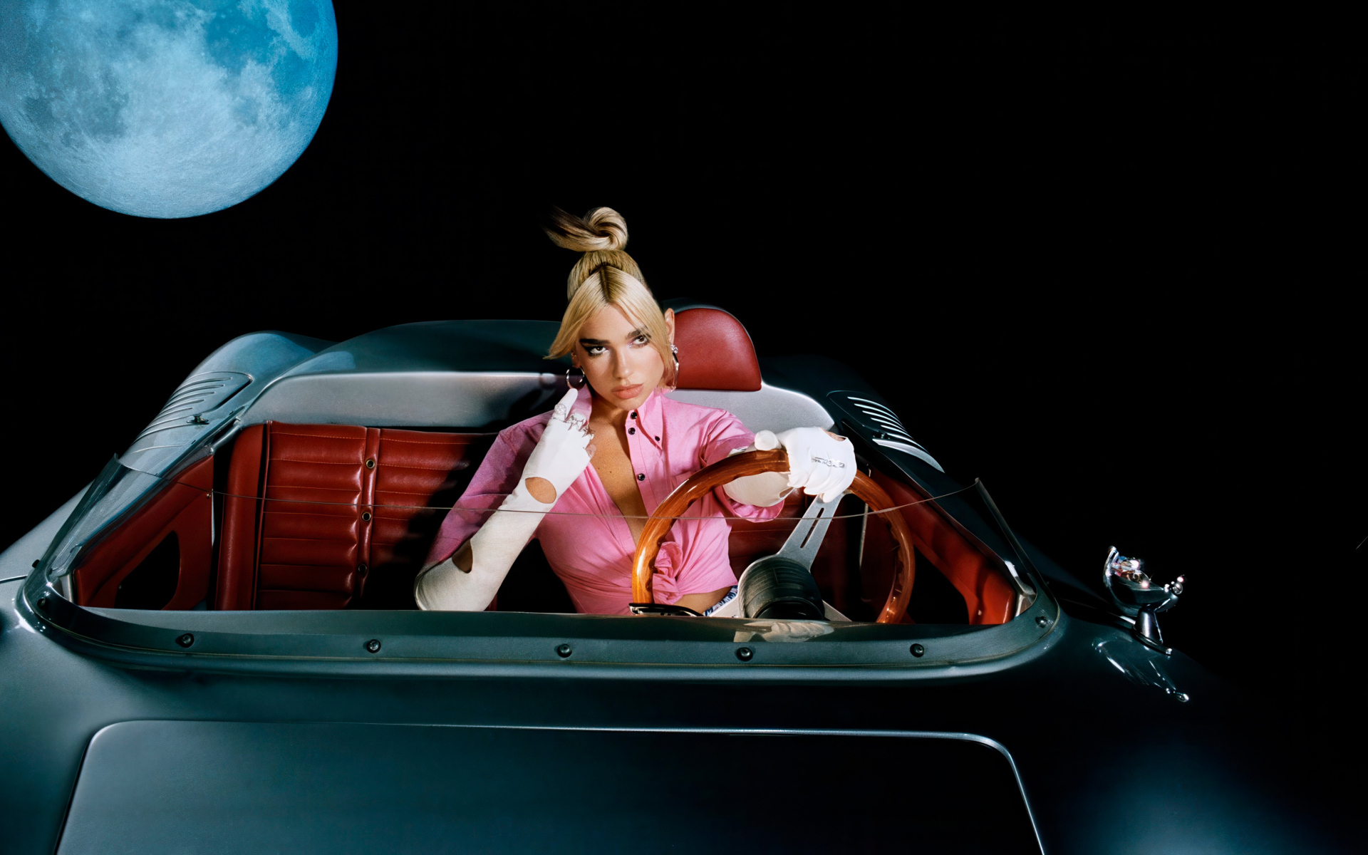 Певица Дуа Липа сидит в машине на фоне луны