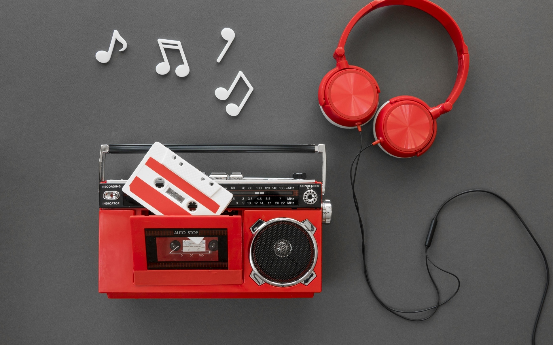 Магнитофон с кассетой, наушниками и нотами на сером фоне