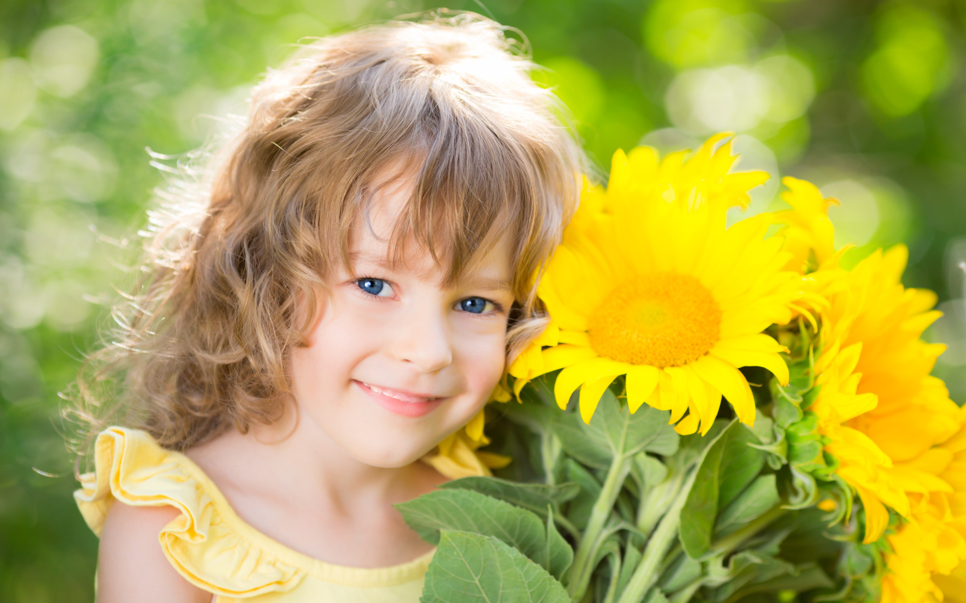 Красивая голубоглазая девочка с букетом подсолнухов