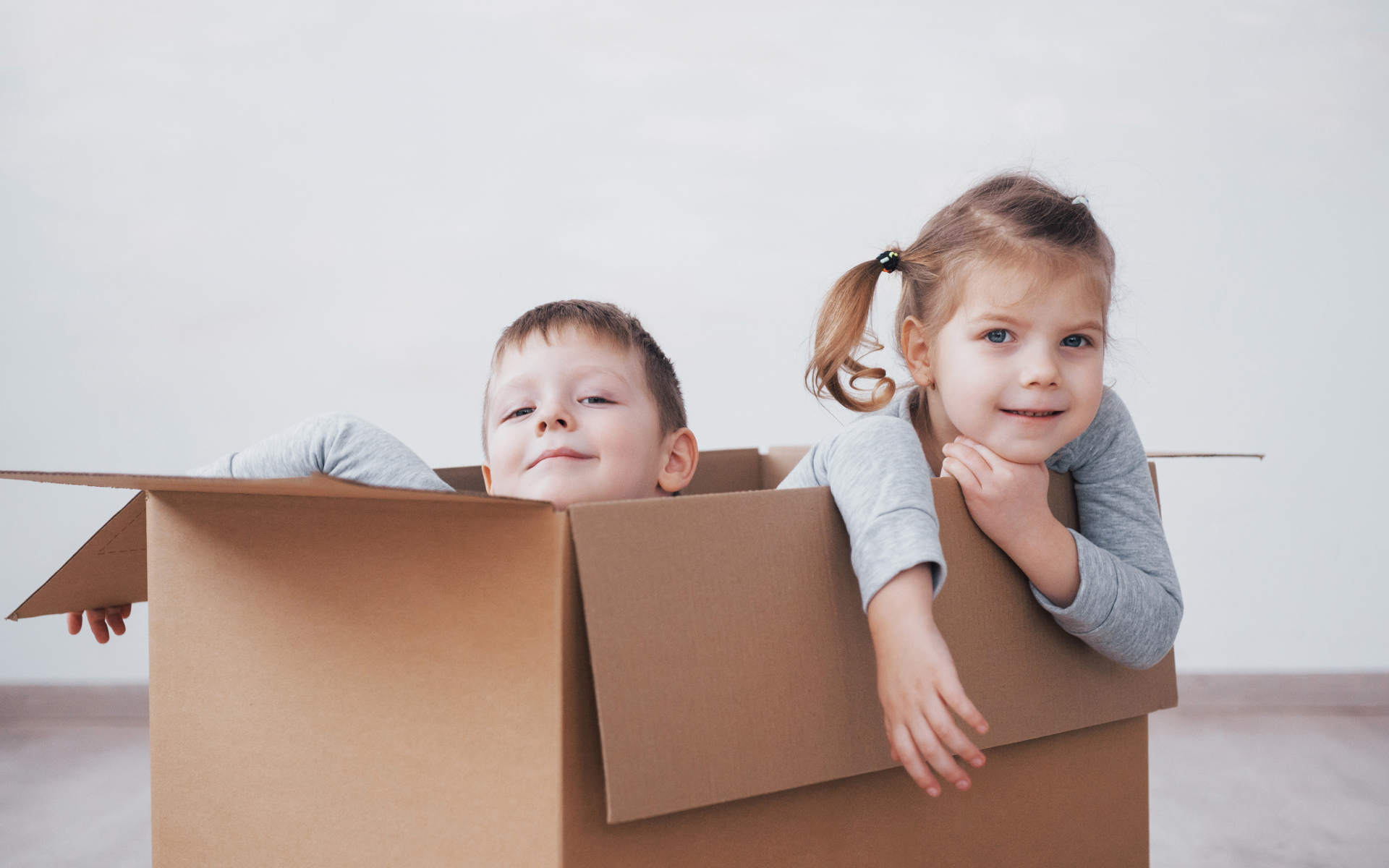 Брат и сестра сидят в картонной коробке