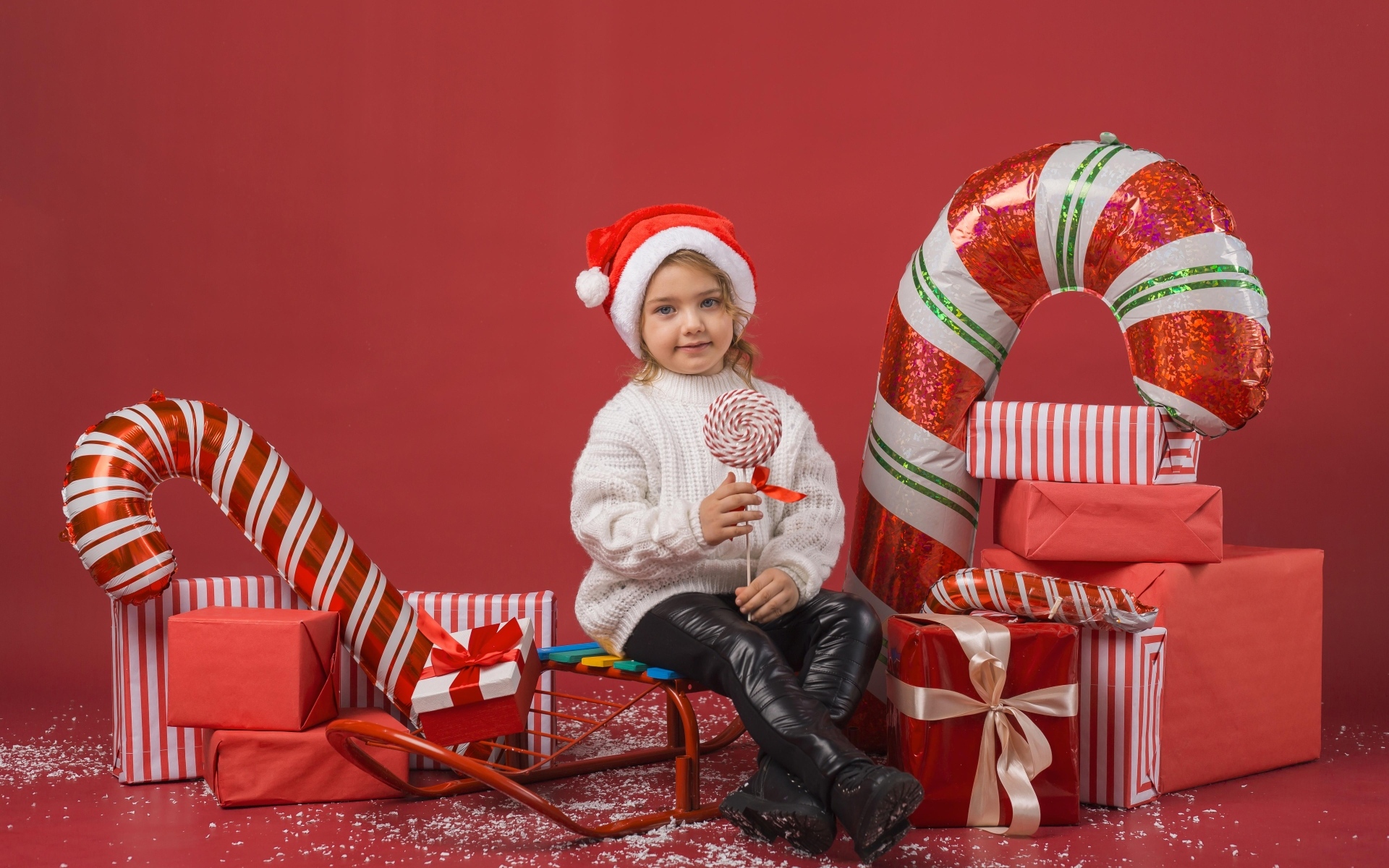 Маленькая девочка с новогодними подарками на красном фоне