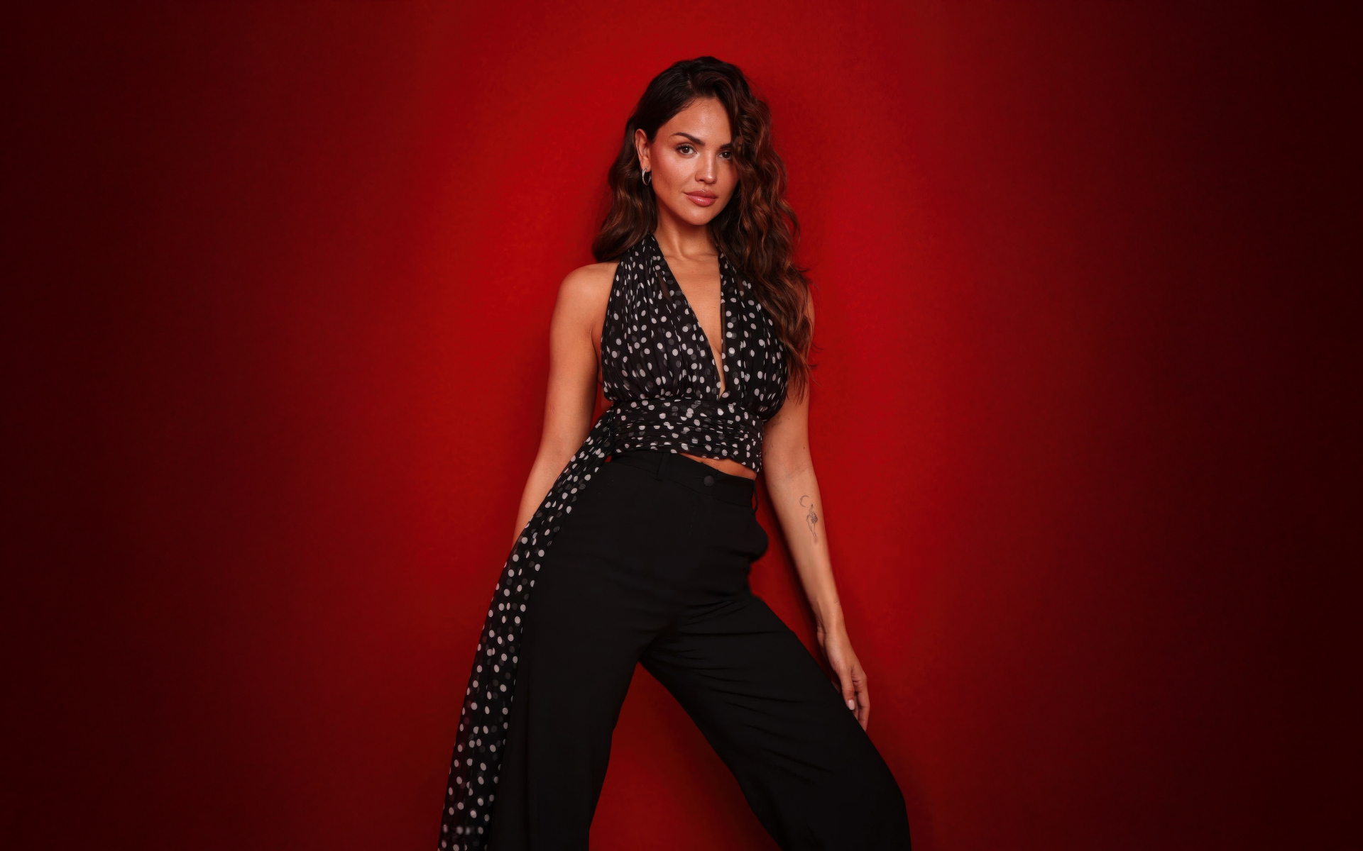 Мексиканская актриса Эйса Гонсалес в черном костюме на красном фоне