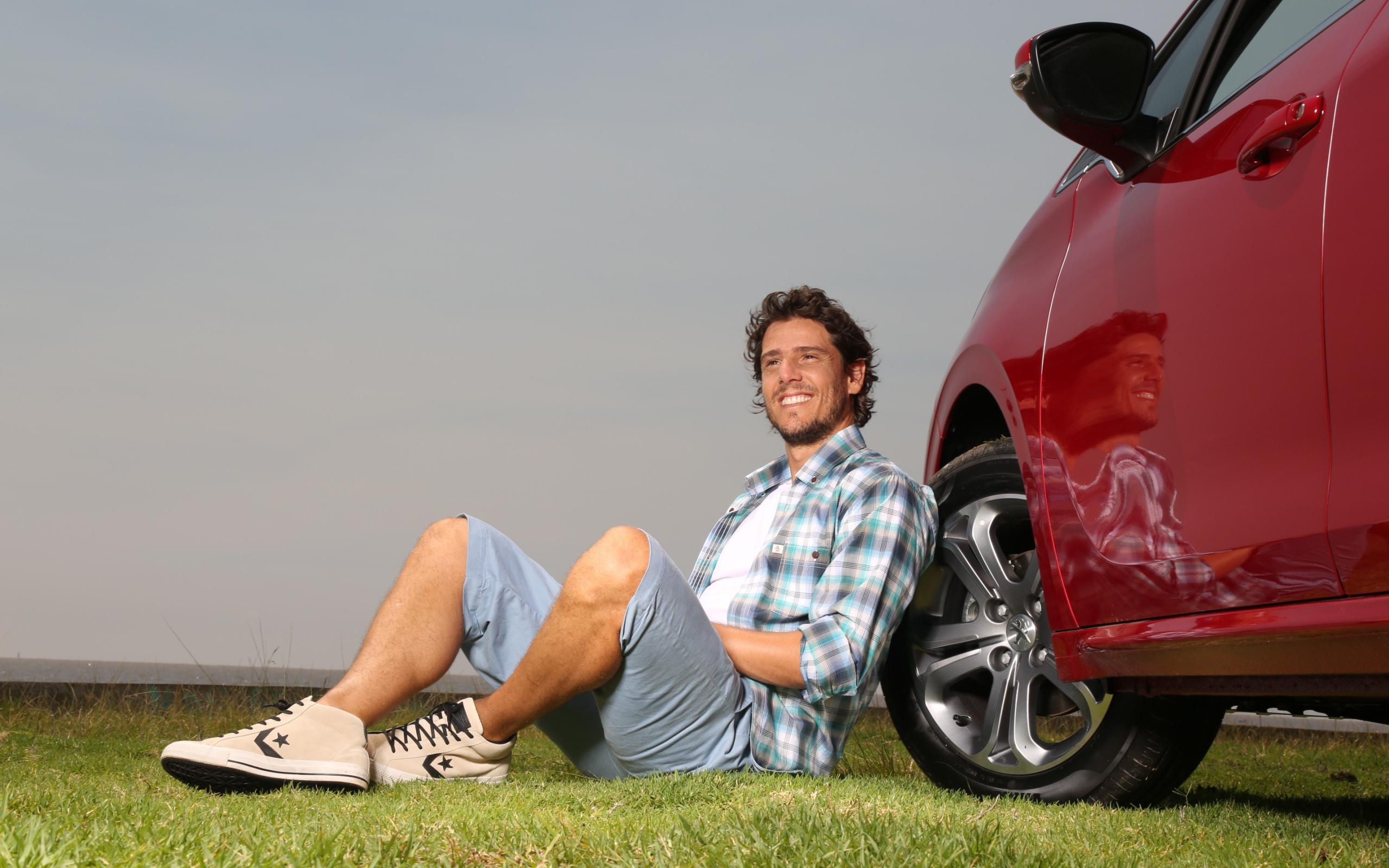 Мужчина сидит у колеса своего автомобиля