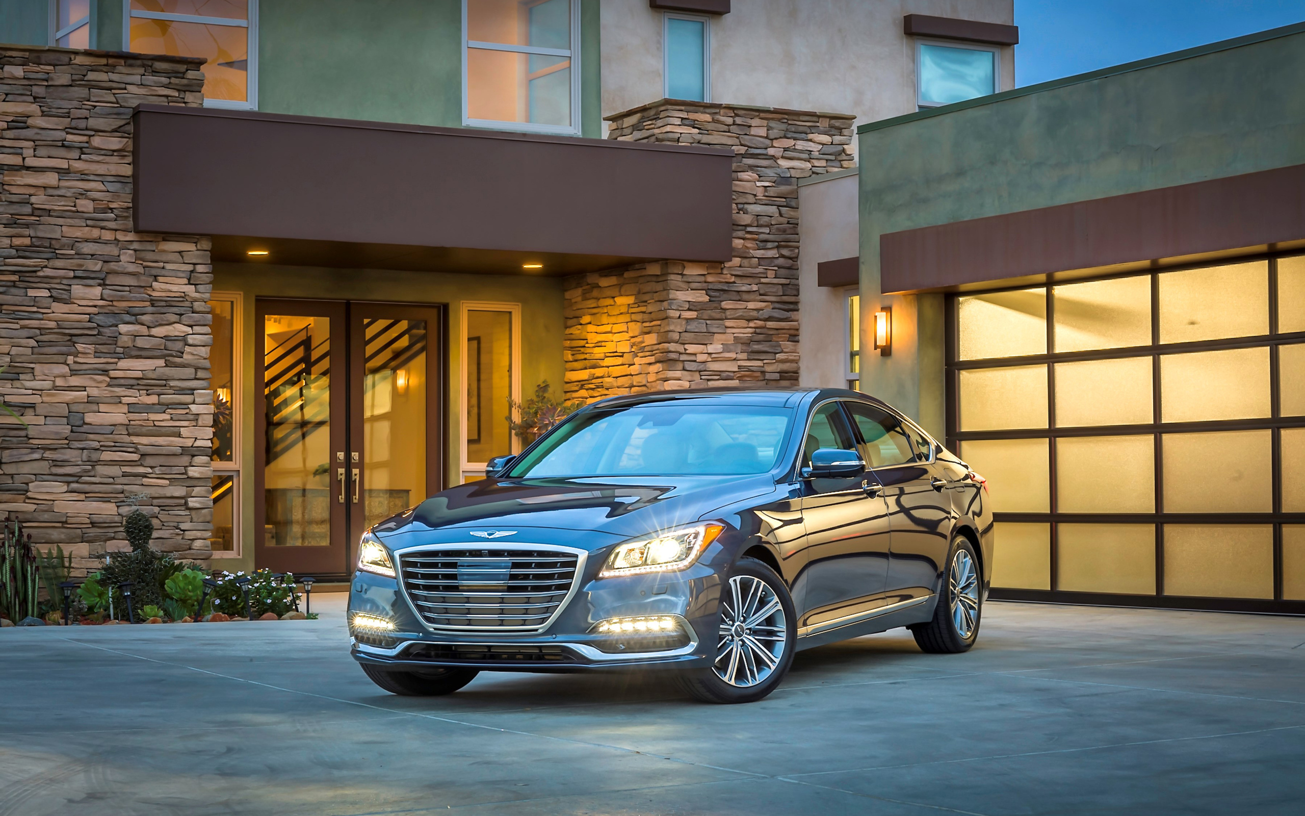 Серебристый автомобиль Genesis G80 с включенными фарами