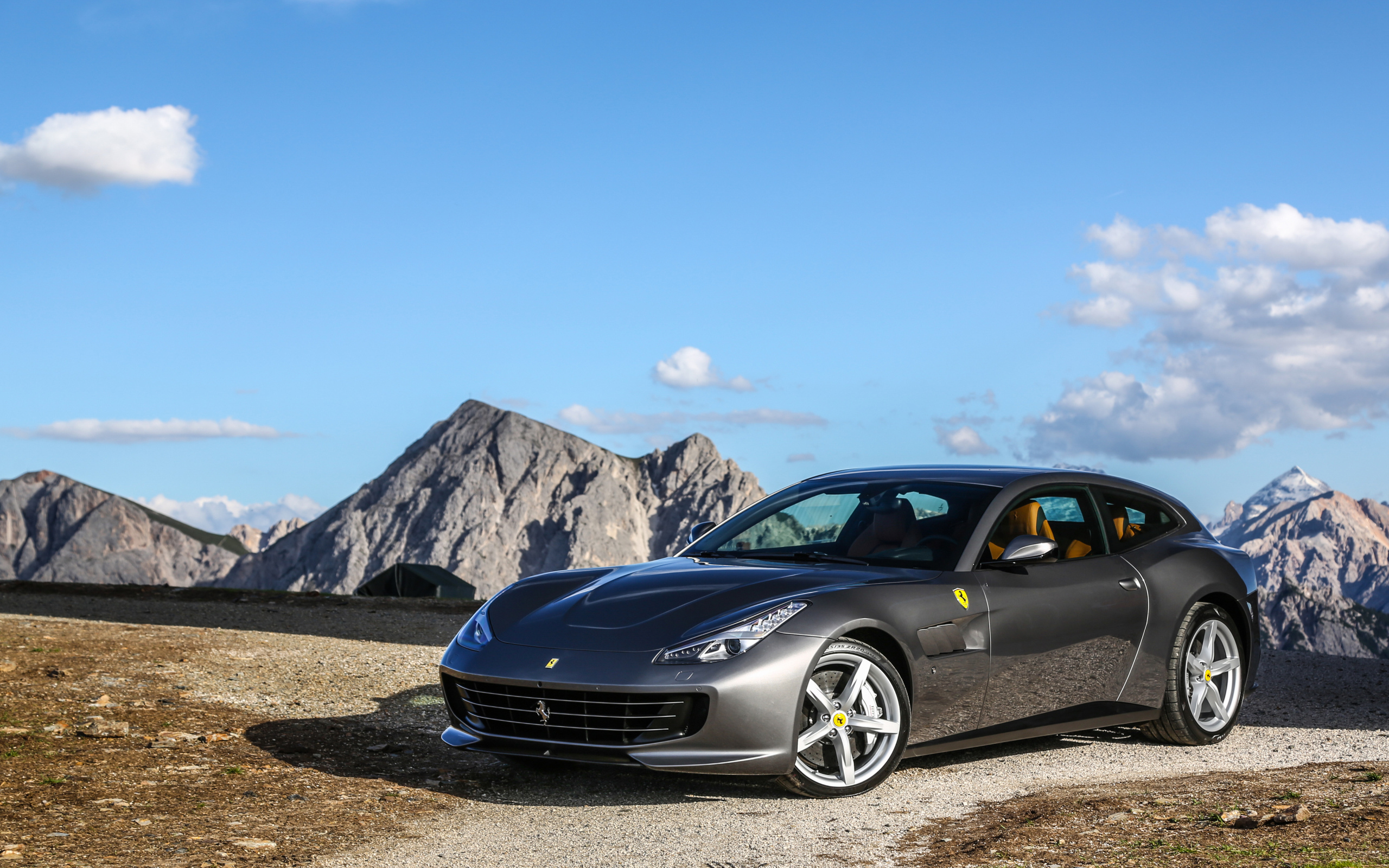 Серебристый автомобиль Ferrari GTC4Lusso на фоне голубого неба 