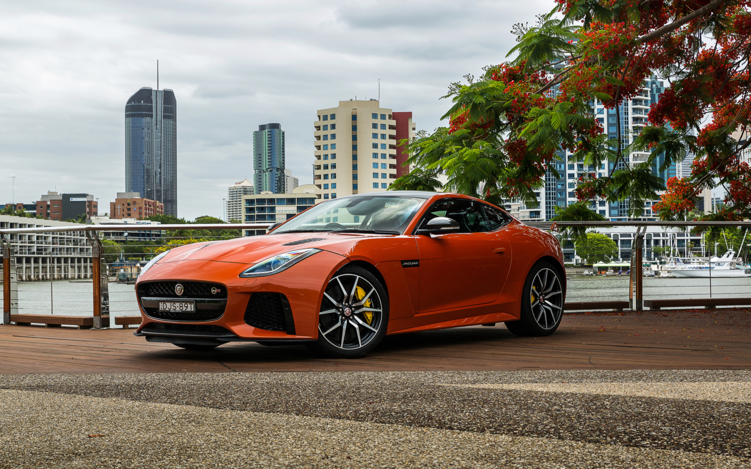 Оранжевый автомобиль Jaguar F-Type на фоне небоскребов 