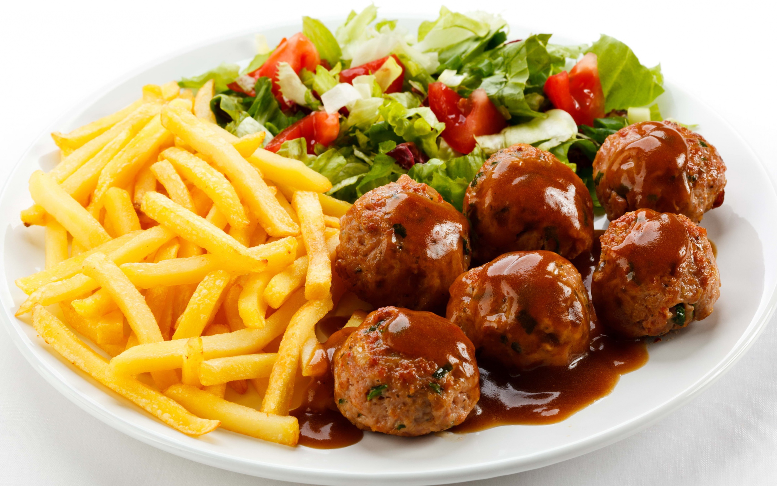 Картофель фри на белой тарелке с салатом и фрикадельками