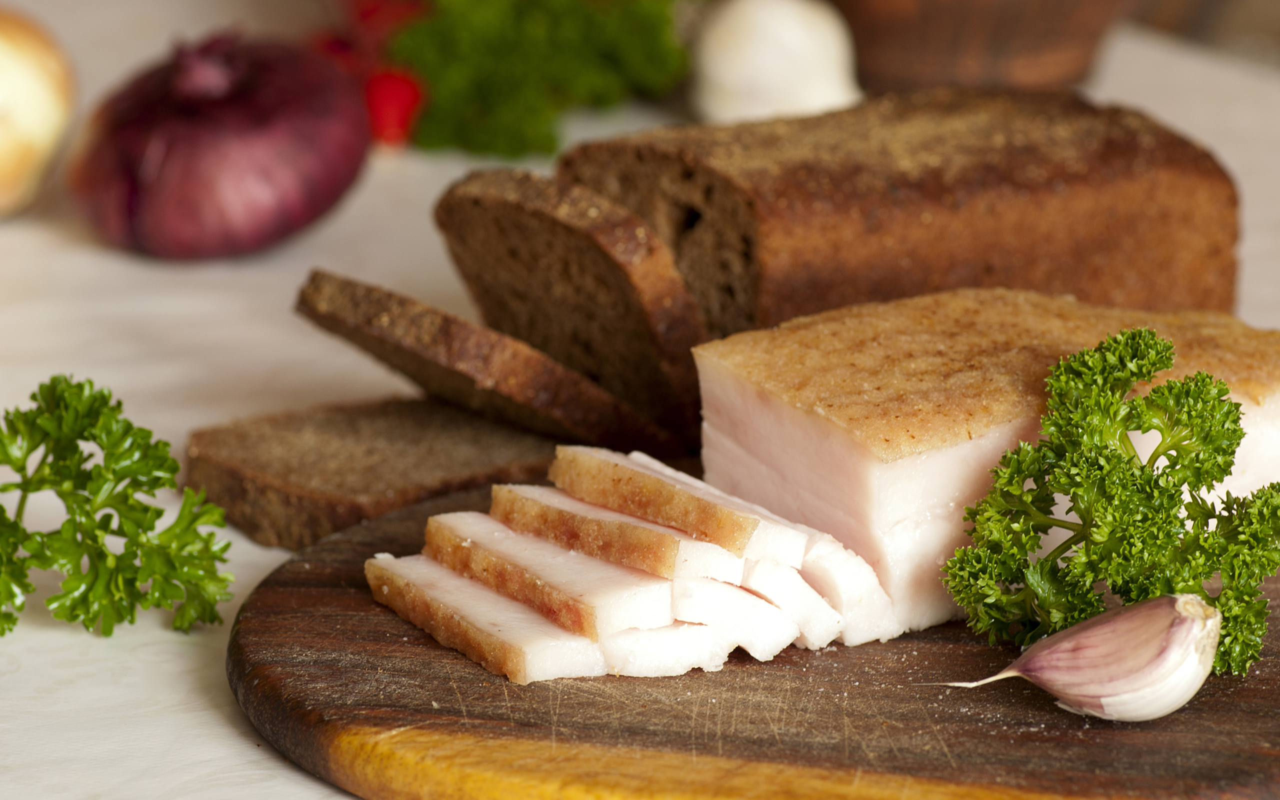 Нарезанное кусочками сало и черный хлеб на разделочной доске