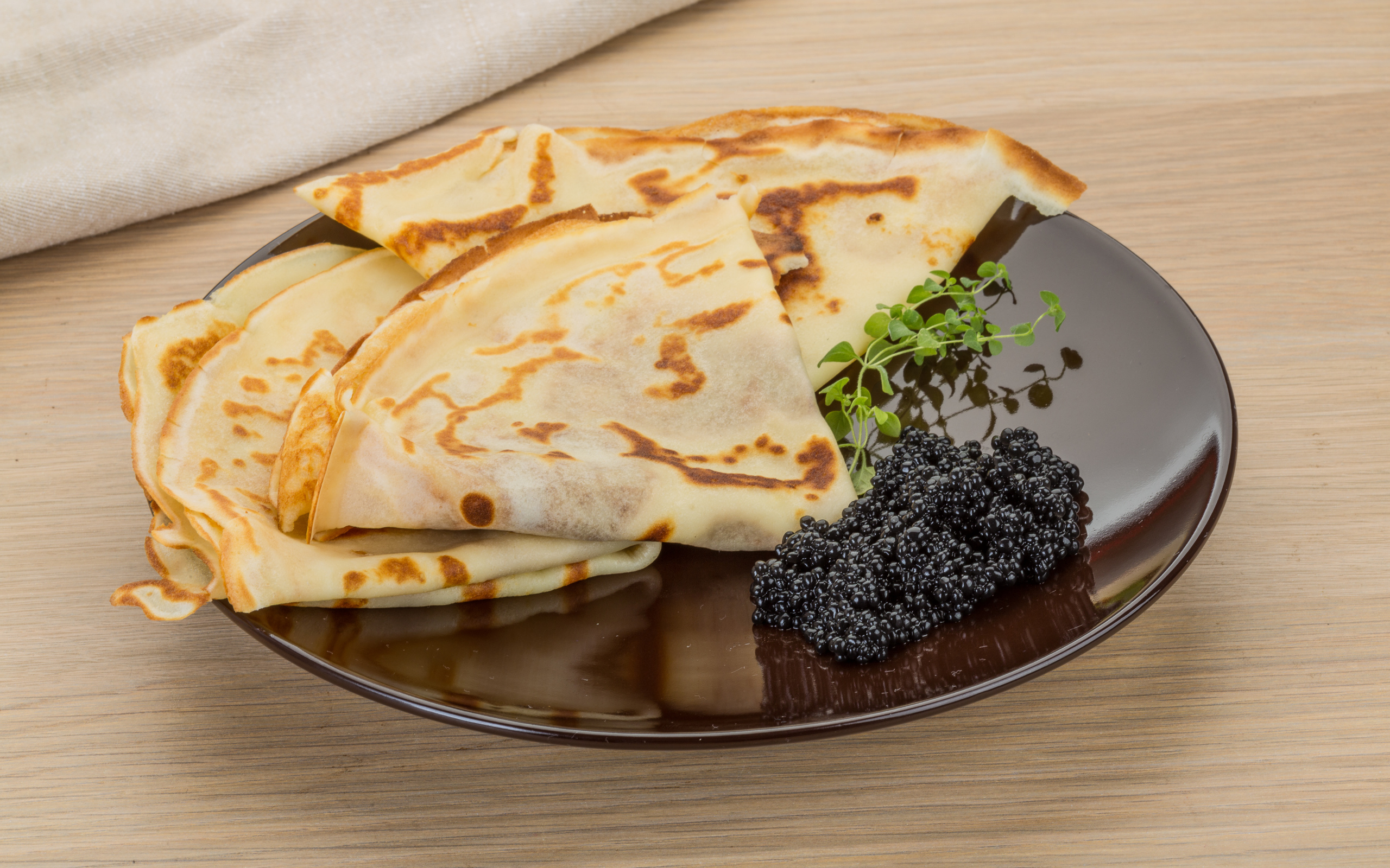 Тонкие блины на тарелке с черной икрой