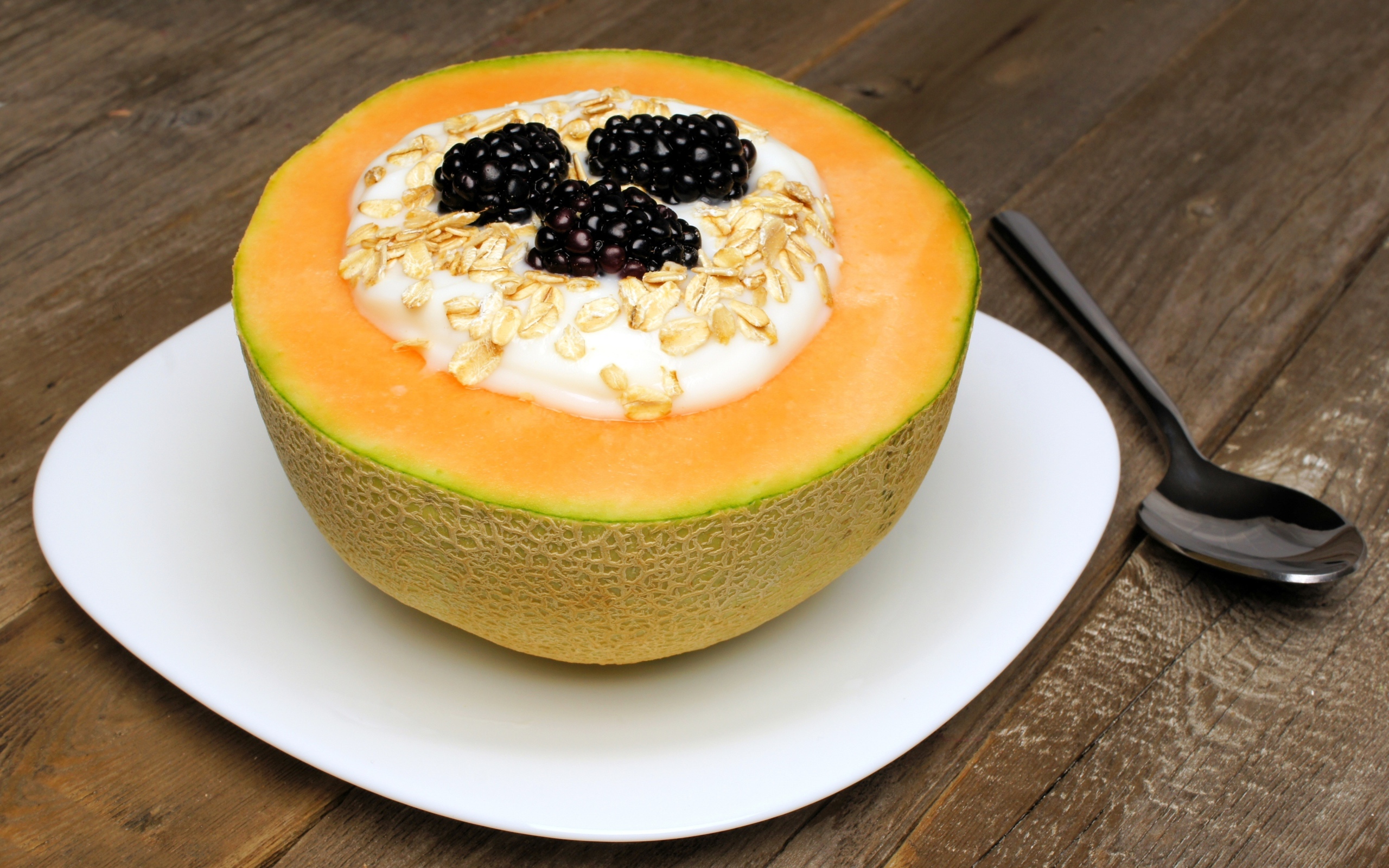 Йогурт с ежевикой и овсянкой в тарелке из свежей дыни на завтрак