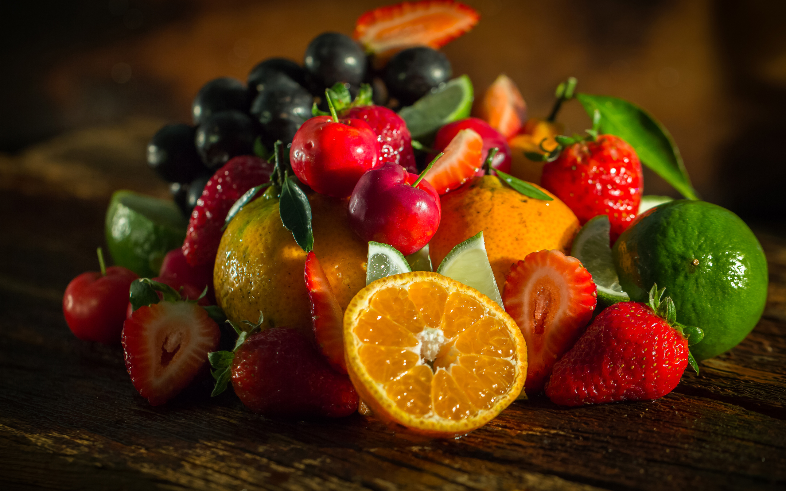 Свежие кусочки апельсина, лимона и ягоды вишни и клубники на столе