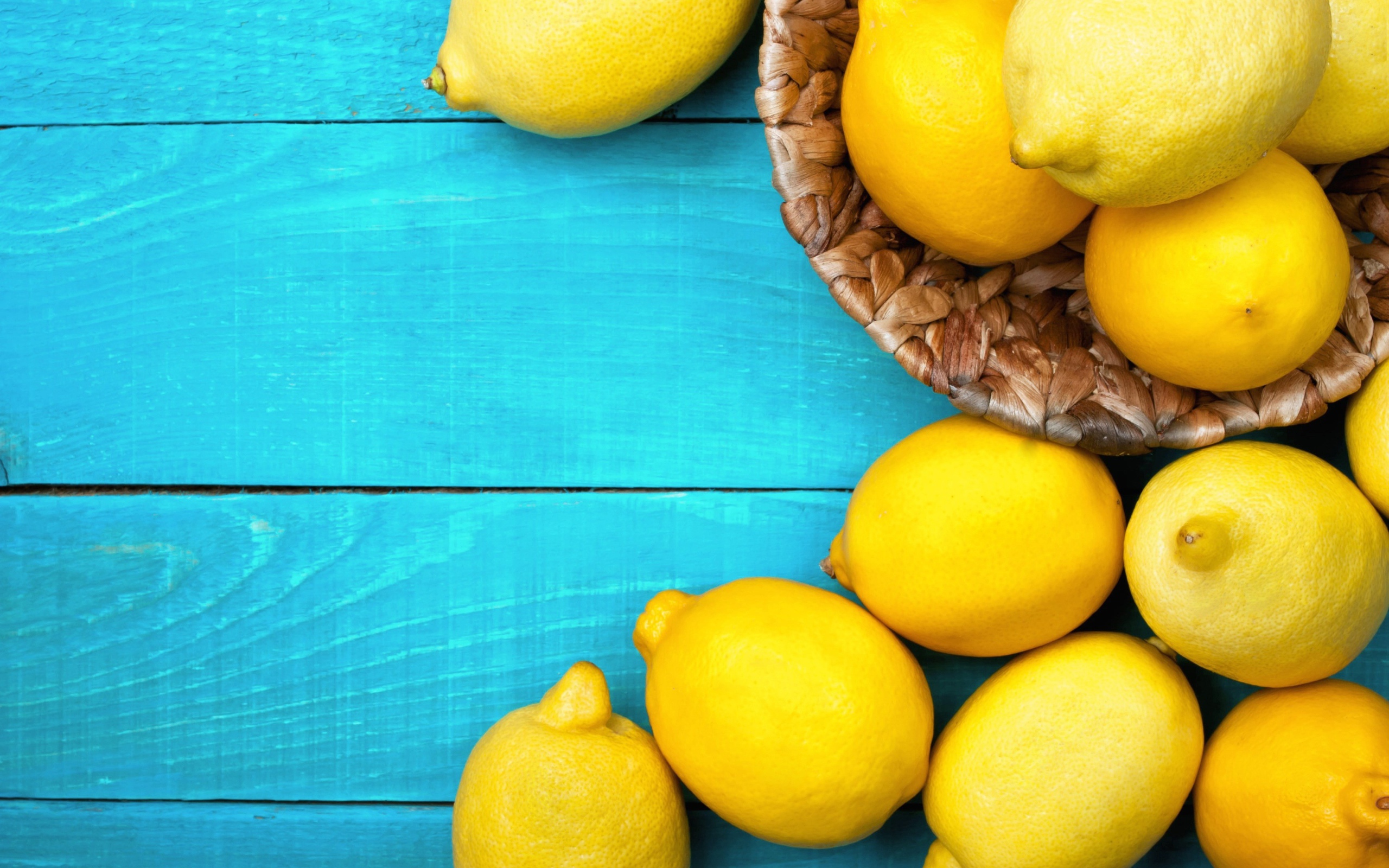 Свежие желтые лимоны лежат на голубой поверхности стола