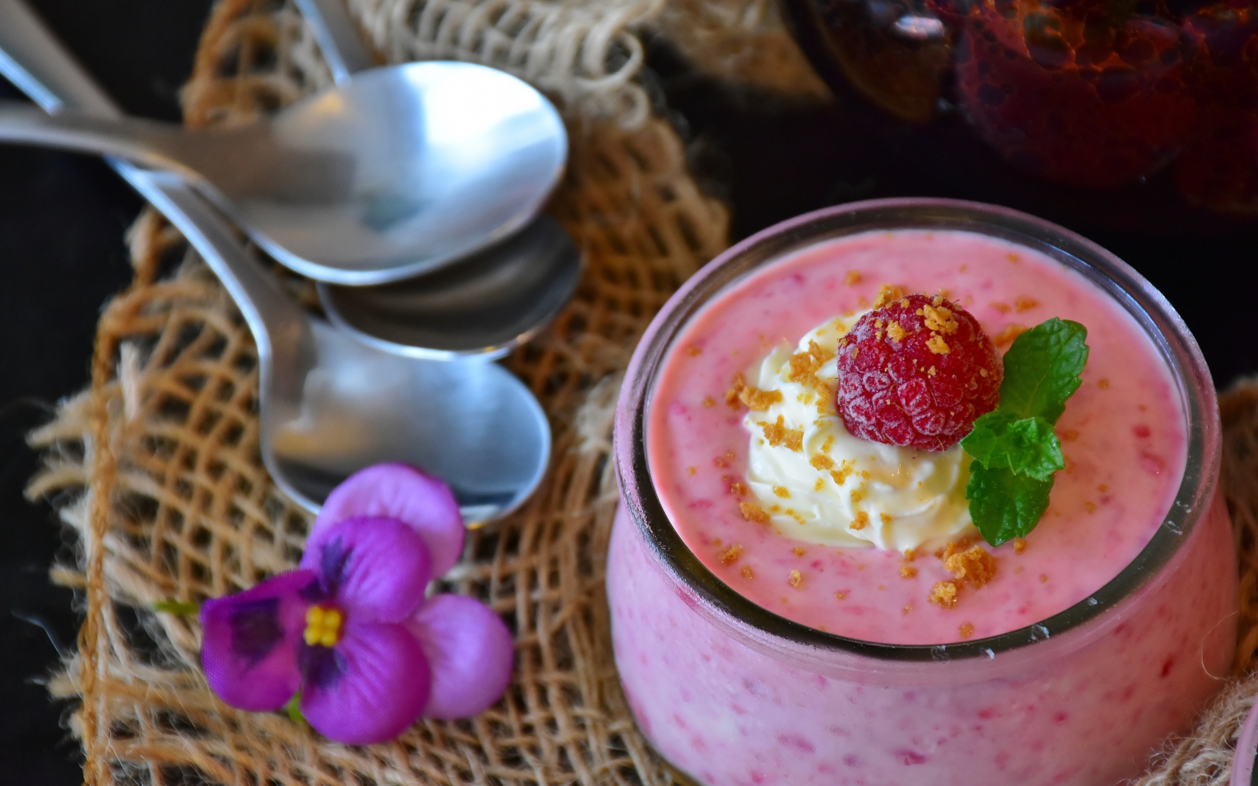 Десерт с малиной и кремом на столе с ложками