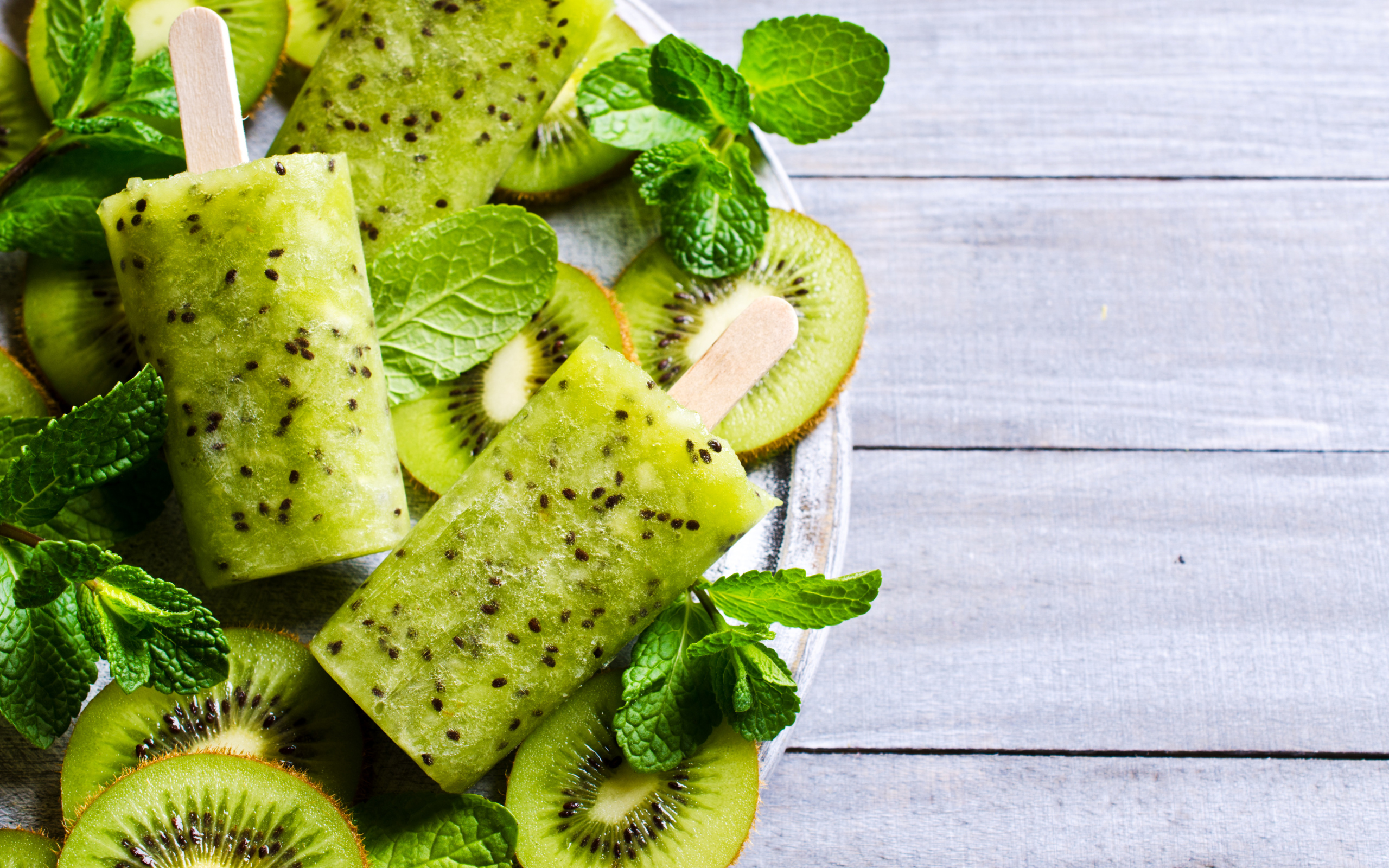 Мороженое с киви и листиками мяты на деревянном столе