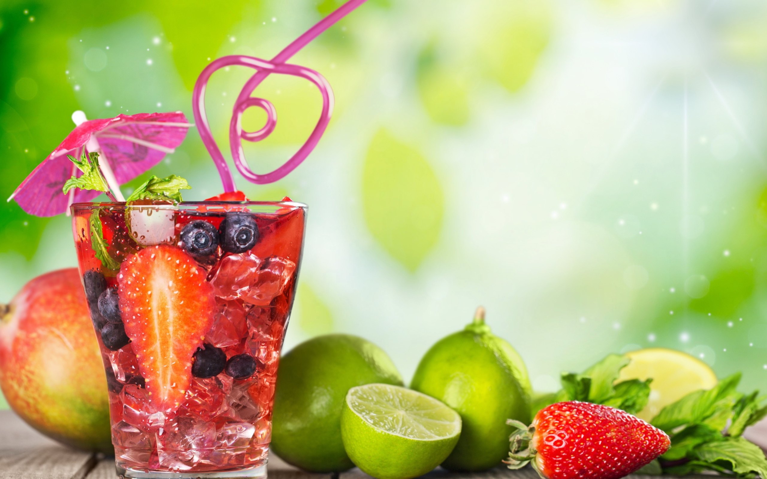 Коктейль с клубникой и ягодами черники в стакане со льдом на столе с лаймами и клубникой