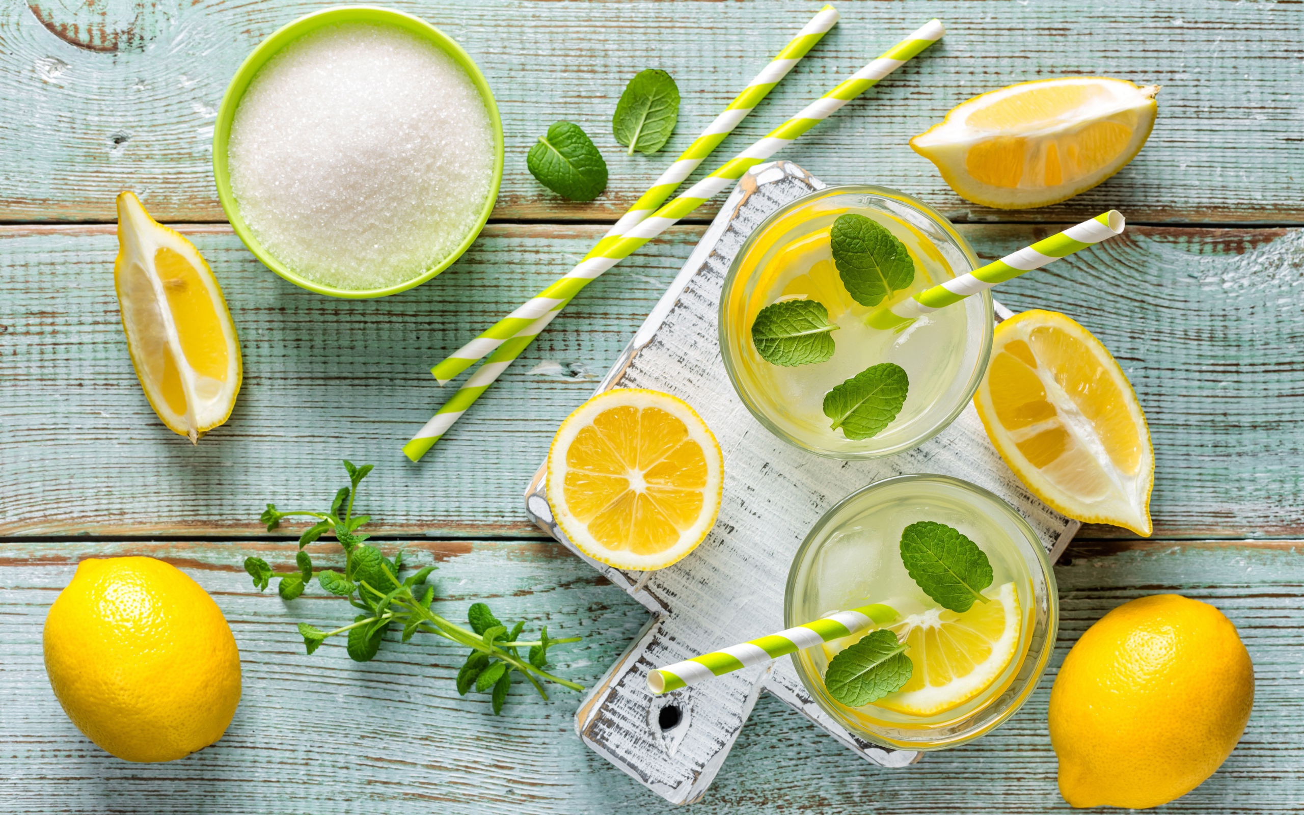 Два стакана с лимонадом, мятой, свежими лимонами и сахаром на столе