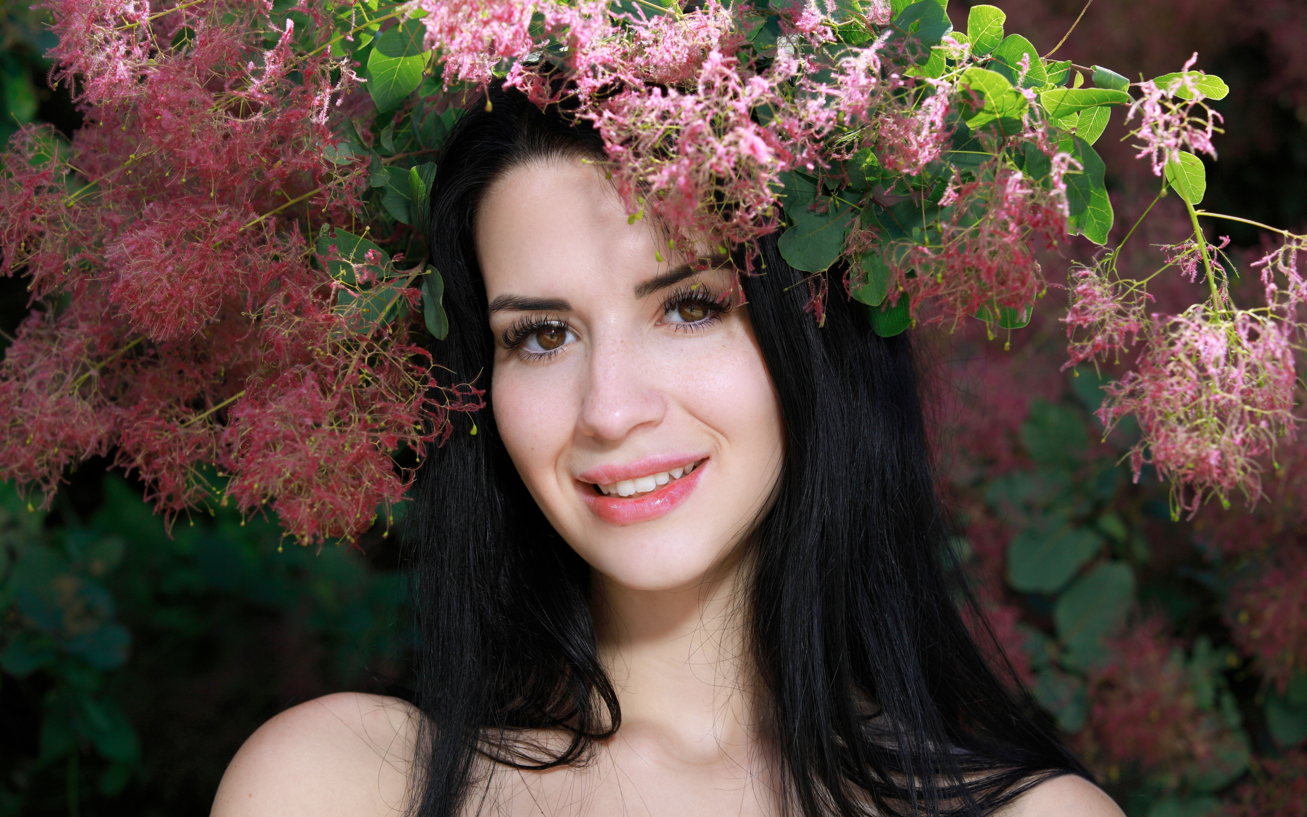 Красивая брюнетка стоит у цветущей ветки