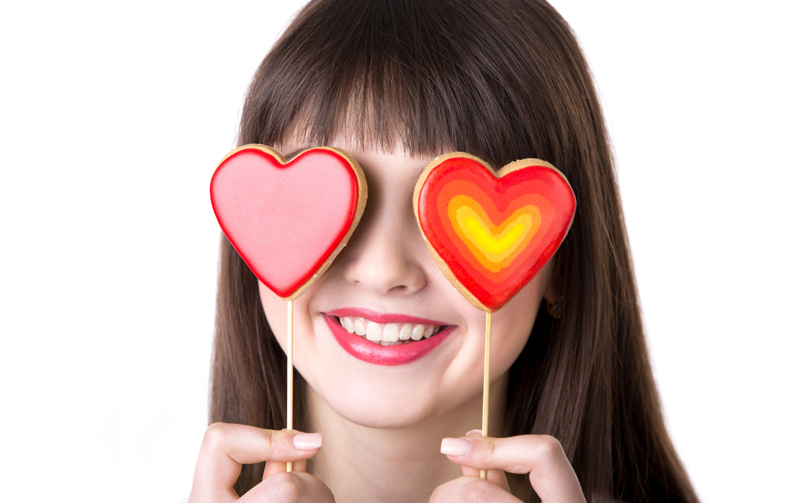 Красивая девушка шатенка закрыла глаза леденцами в форме сердца