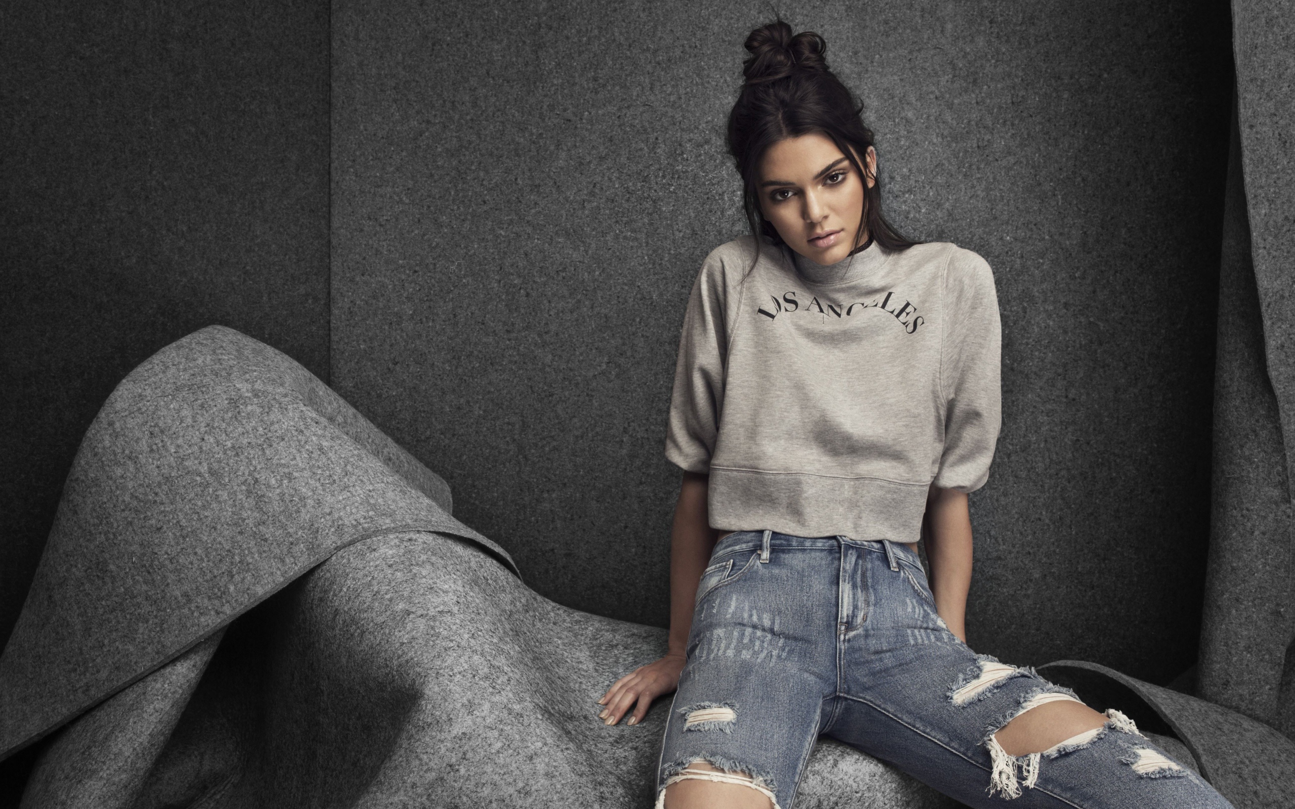 Модель Кендалл Дженнер в рваных джинсах на сером фоне