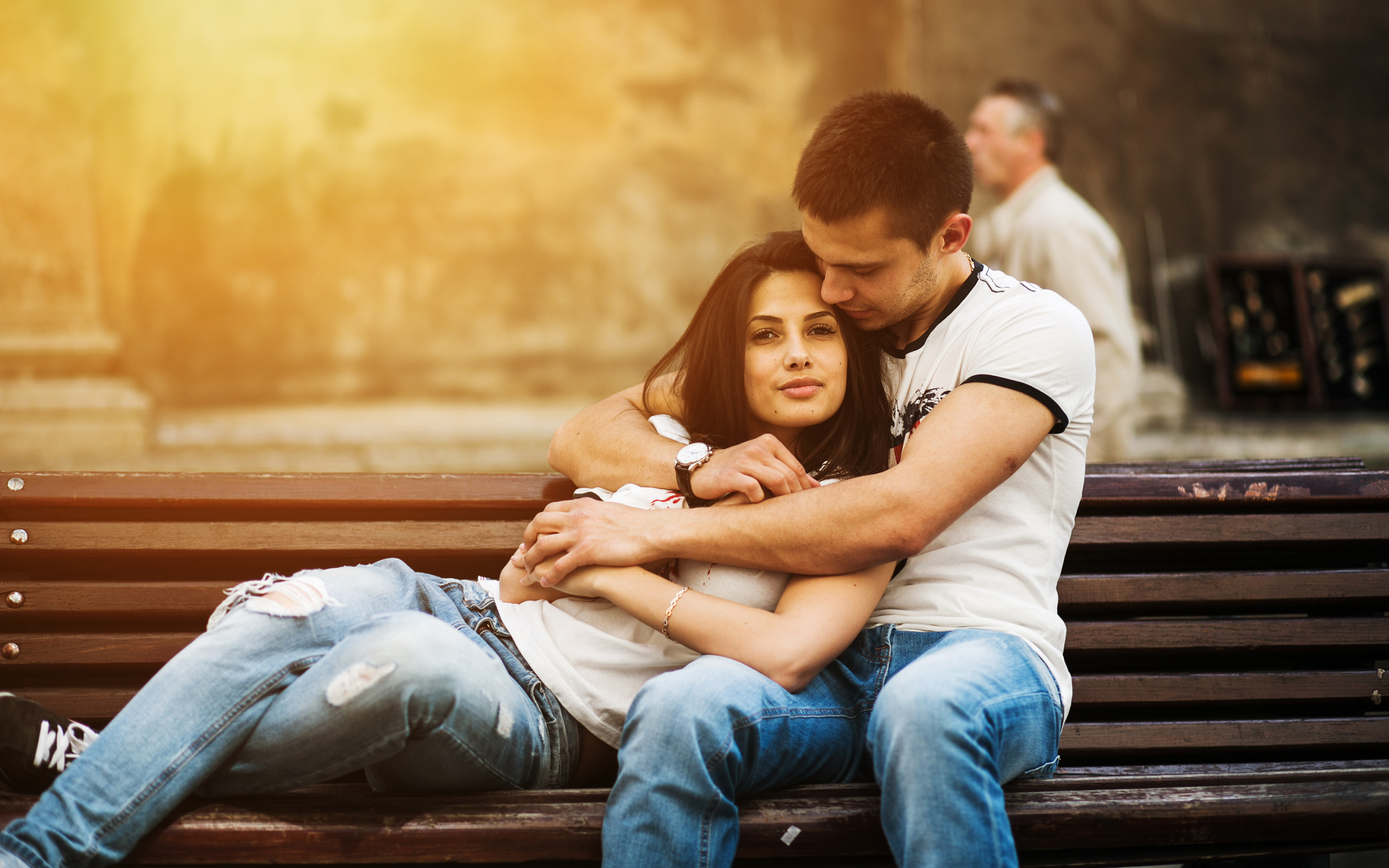 Влюбленная пара сидит на деревянной лавке в парке