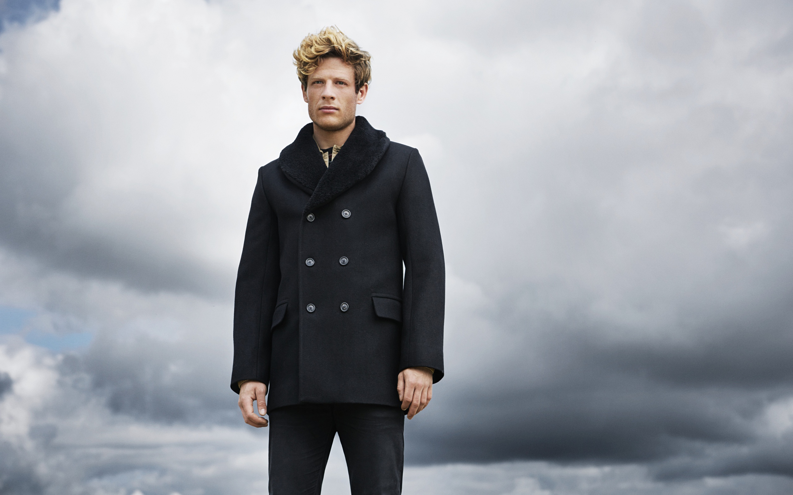 Актер Джеймс Нортон в черном пальто на фоне неба