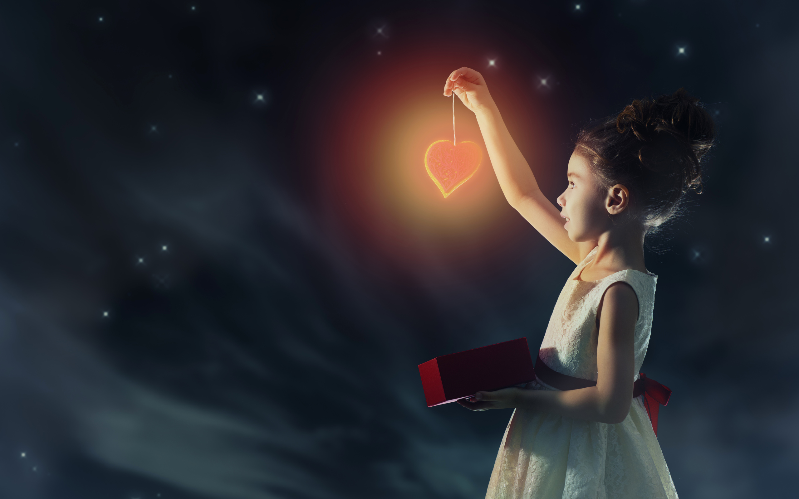 Девочка в красивом белом платье держит в руках сердечко