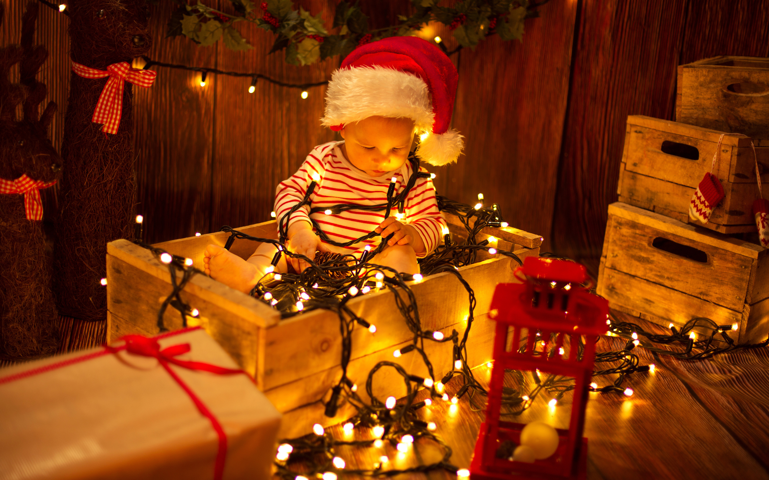 Маленький мальчик сидит в коробке с новогодней гирляндой