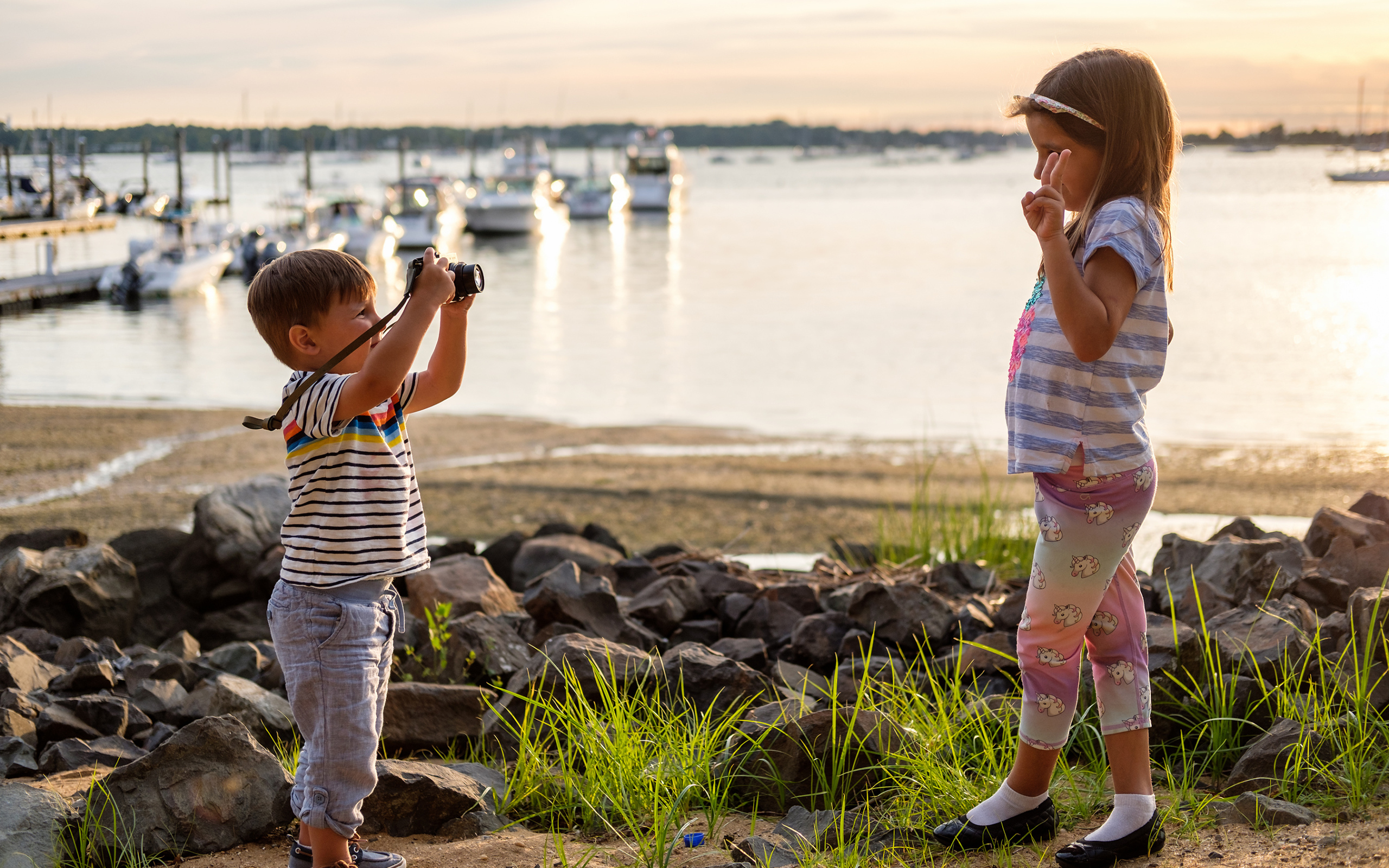 Маленький мальчик фотографирует девочку на берегу