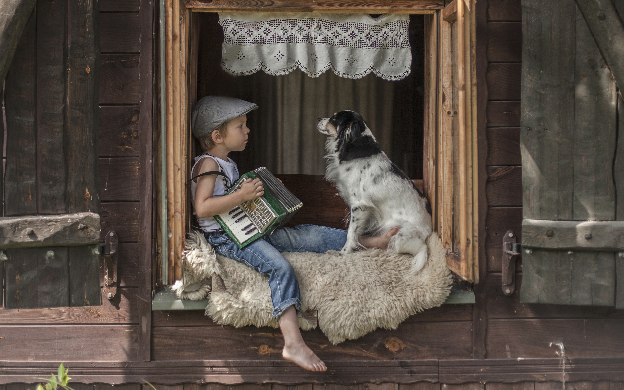 Маленький мальчик с гармошкой сидит на подоконнике с собакой
