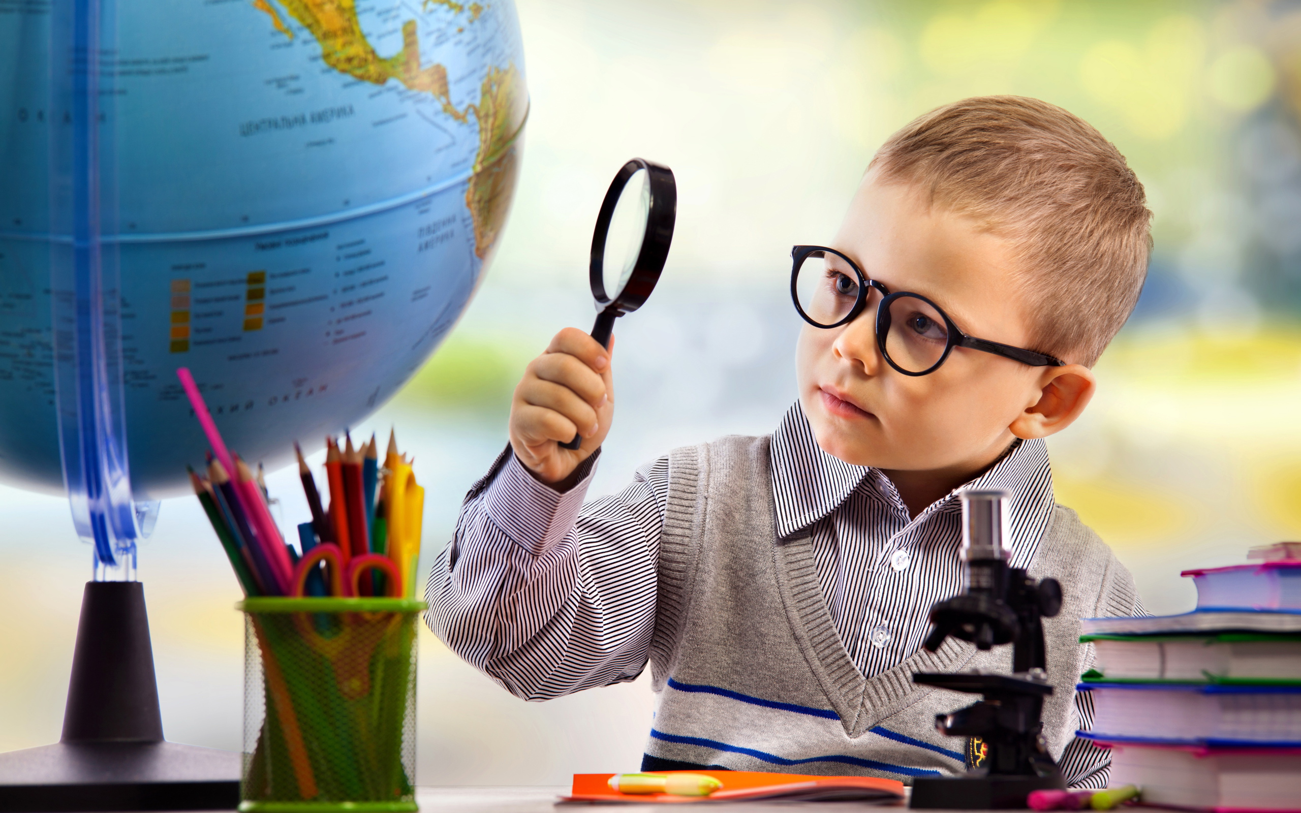 Маленький мальчик в очках исследует глобус
