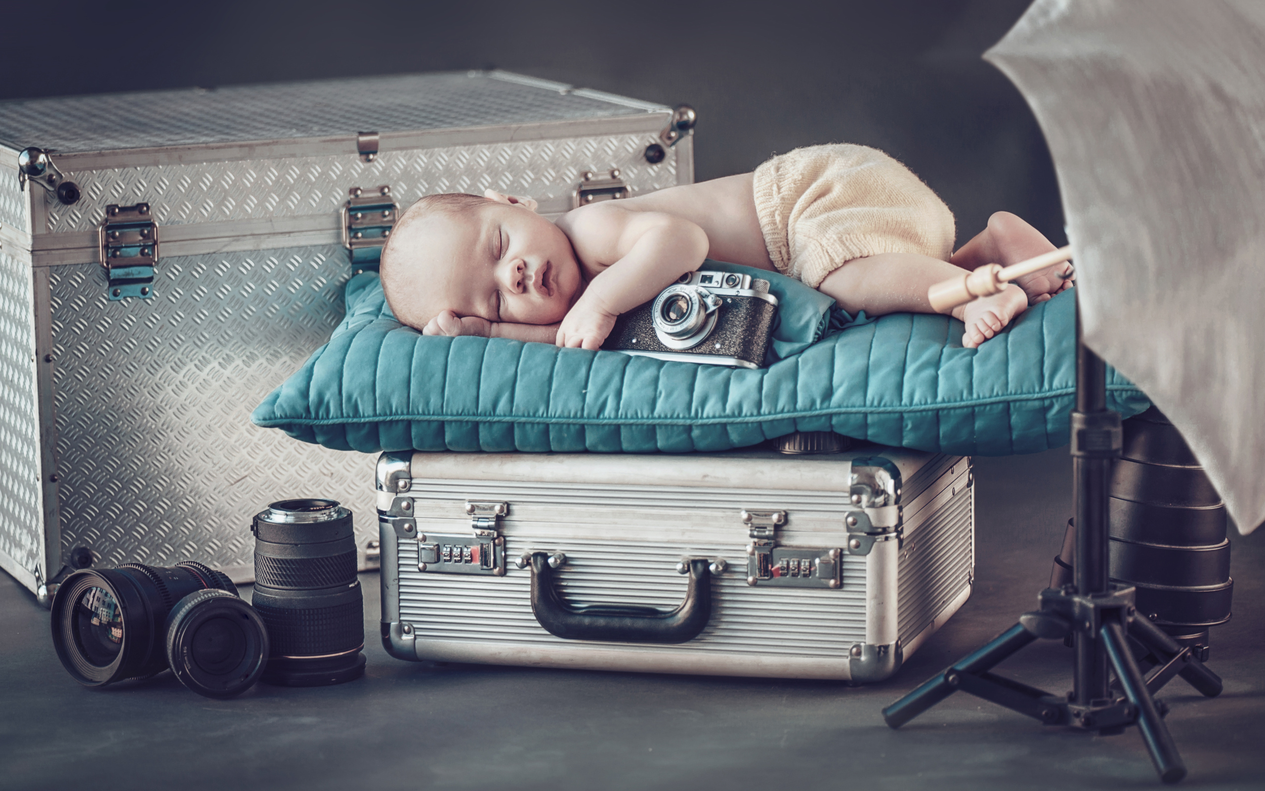 Спящий младенец с фотоаппаратом спит на чемодане