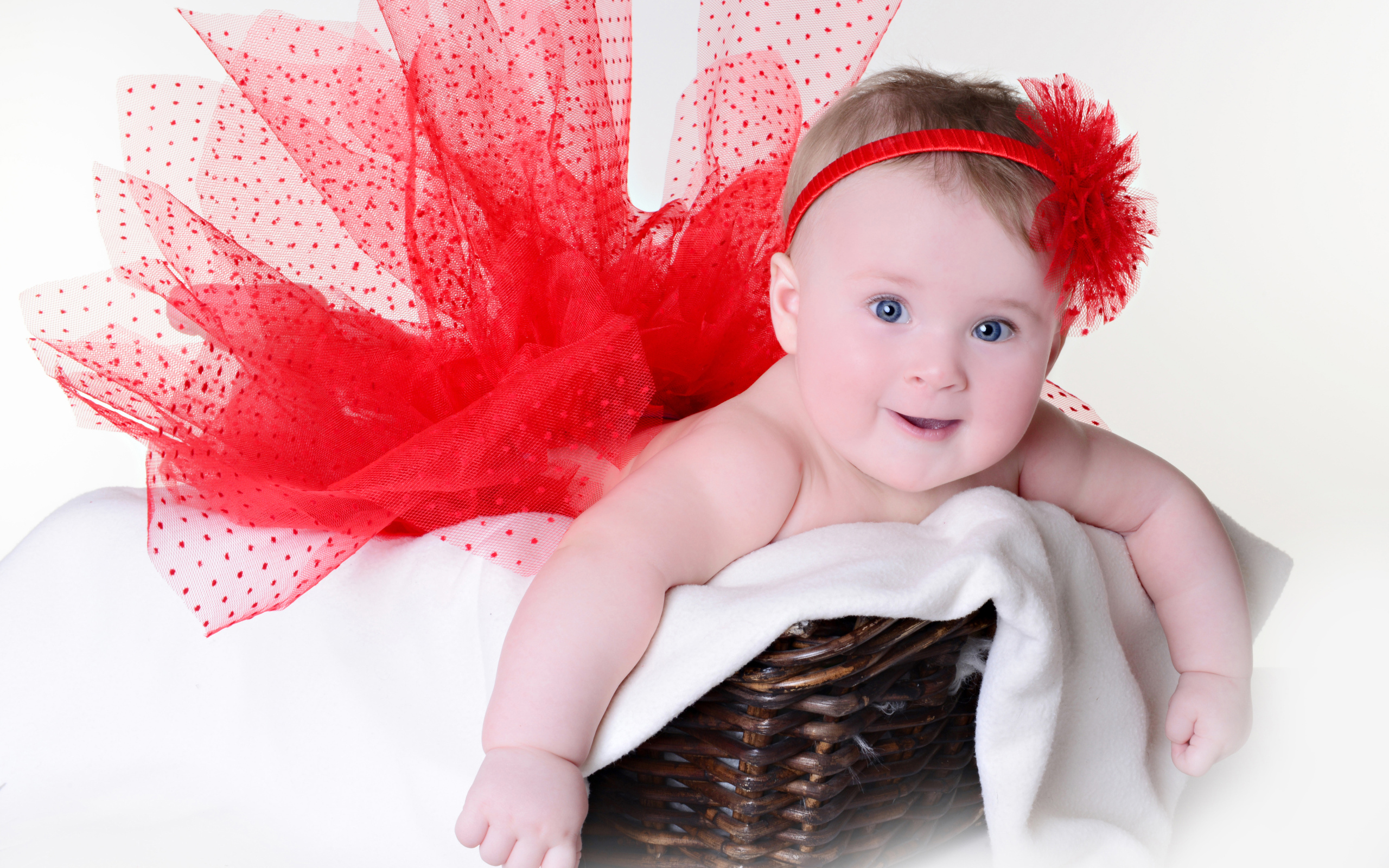 Маленькая голубоглазая девочка в красном красивом платье лежит в корзине